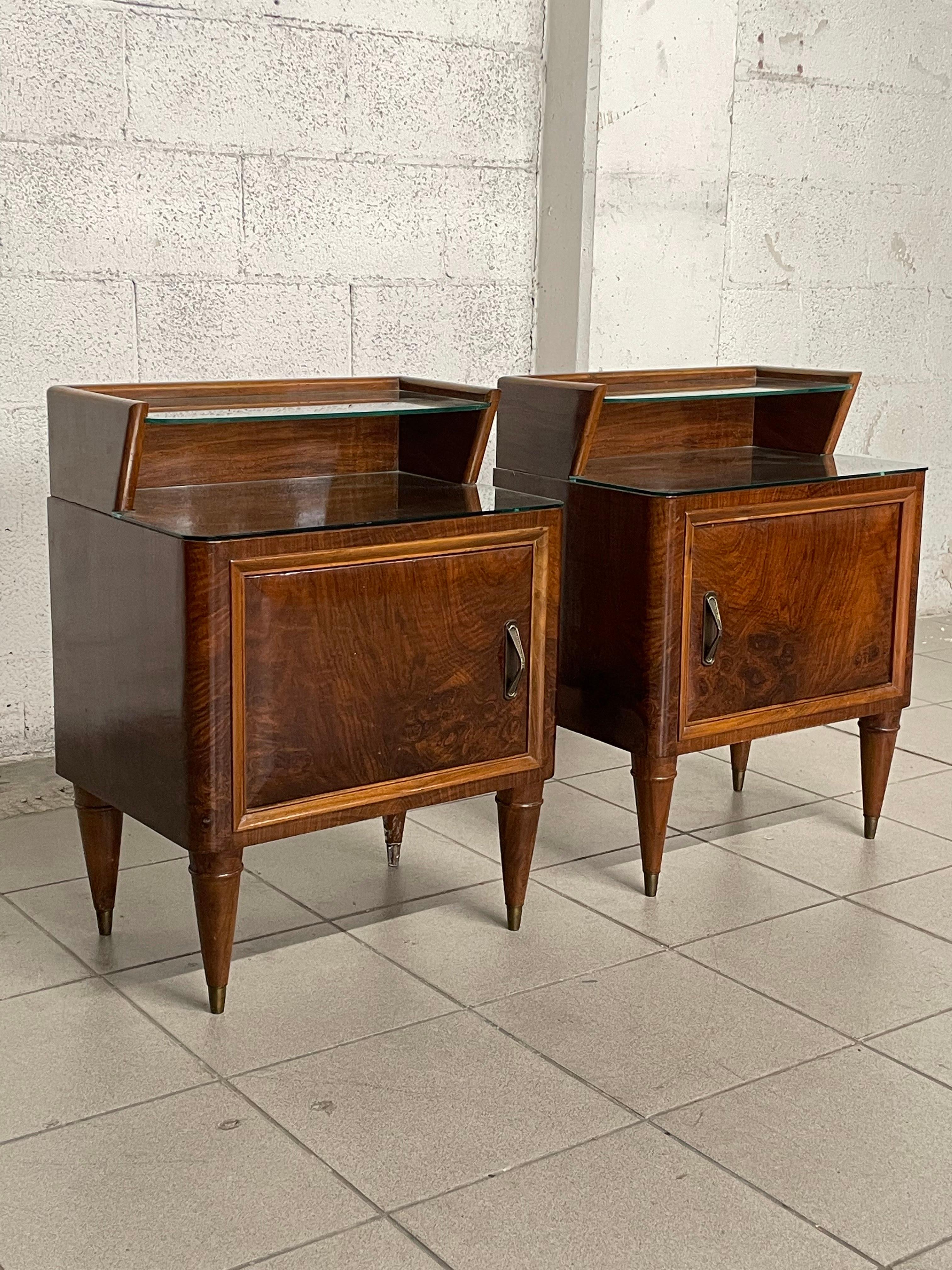 Pair of 1950s bedside tables in mahogany wood with cone feet and brass ferrules.

Glass top and shelf.

The maximum height of the nightstand (shelf height) is 66 cm that of the top is 54 cm.

They have not been restored as they are in good vintage