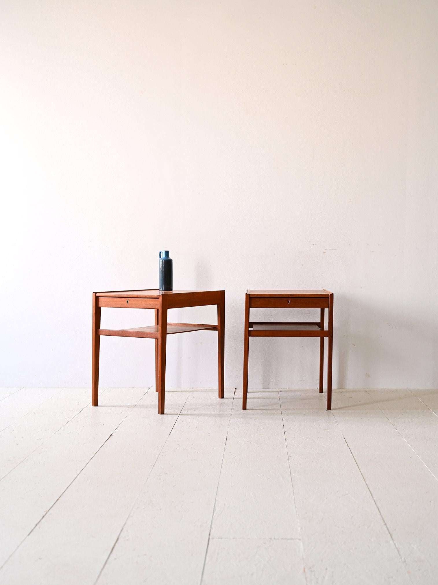 Pair of Scandinavian teak nightstands.

A pair of bedside tables that traces the essence of Scandinavian design from the 1960s. 
Made of teak wood, these nightstands feature a minimalist, cleanly styled frame with slender, square legs that give them