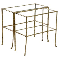 A pair of elegant nesting side tables with brass legs and glass tops from the 1960s.
