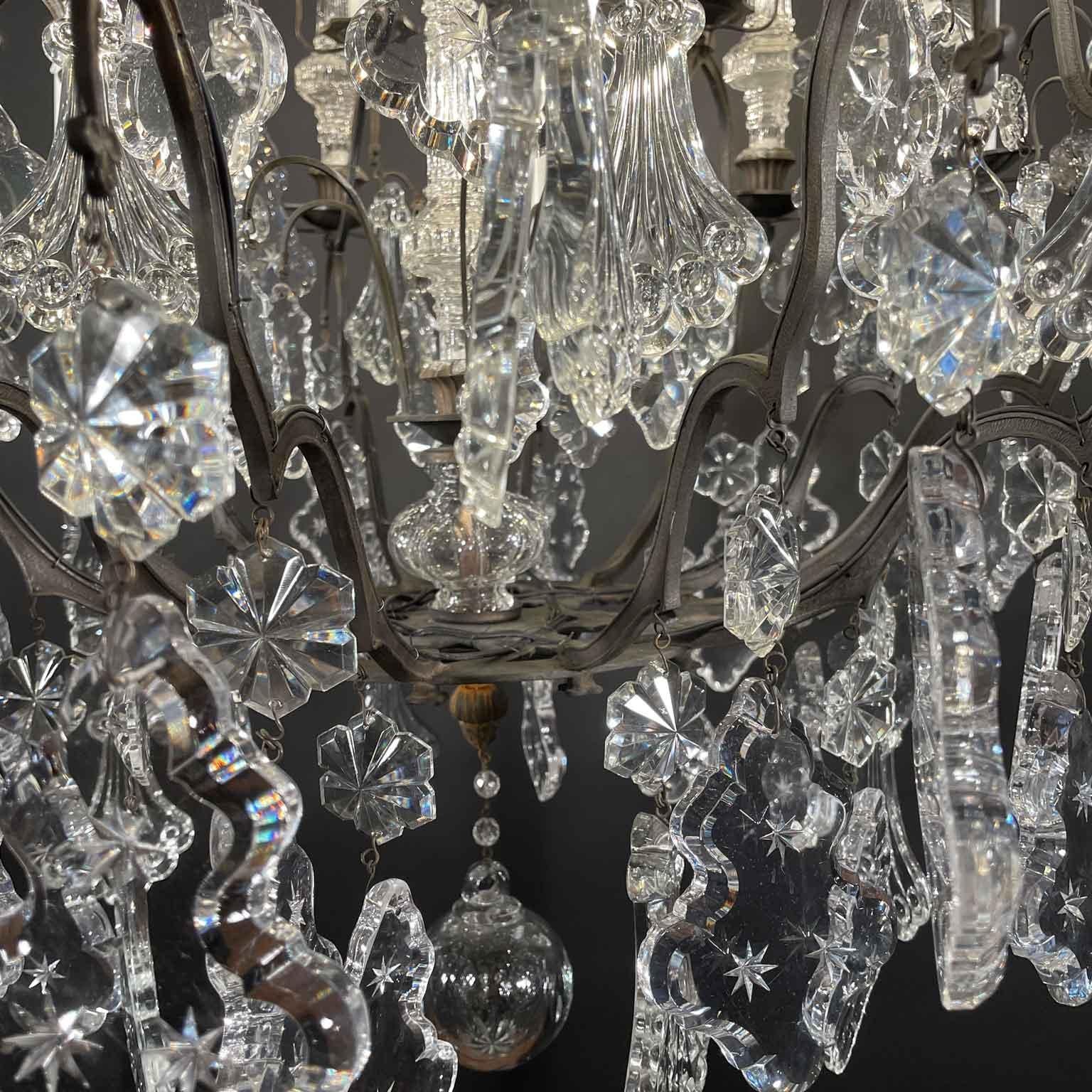Pair Of French Crystal and Bronze Chandeliers with dark patina, twelve lights on two tiers high, excellent condition, circa 1955. This pair of burnished bronze and crystal French chandeliers, made around the mid-20th century, represents timeless