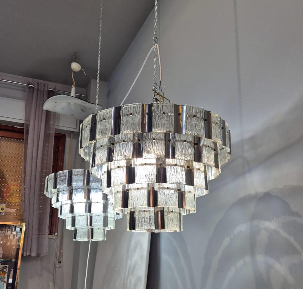 Coppia di lampadari in vetro di murano e metallo. I lampadari sono composti da cinque file di vetri rettangolari in murano alternati da lamelle di metallo.
I vetri non presentano sbeccature e i lampadari, in generale sono in condizioni davvero