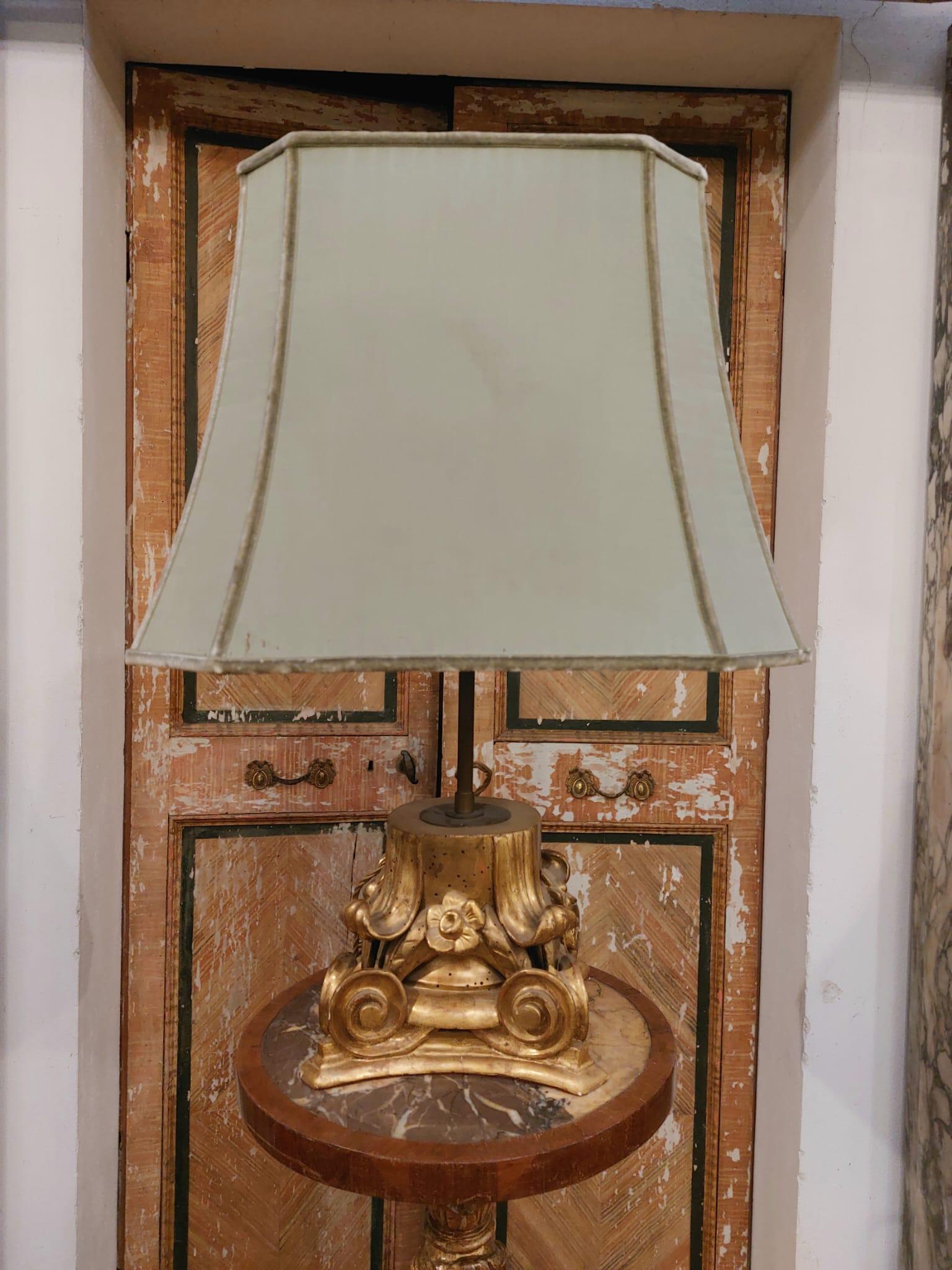 Les deux lampes ont des chapiteaux en bois sculptés de feuilles d'acanthe et dorés à la feuille d'or. Les chapiteaux ont été transformés en lampes, avec un cadre métallique et un tissu de satin vert.