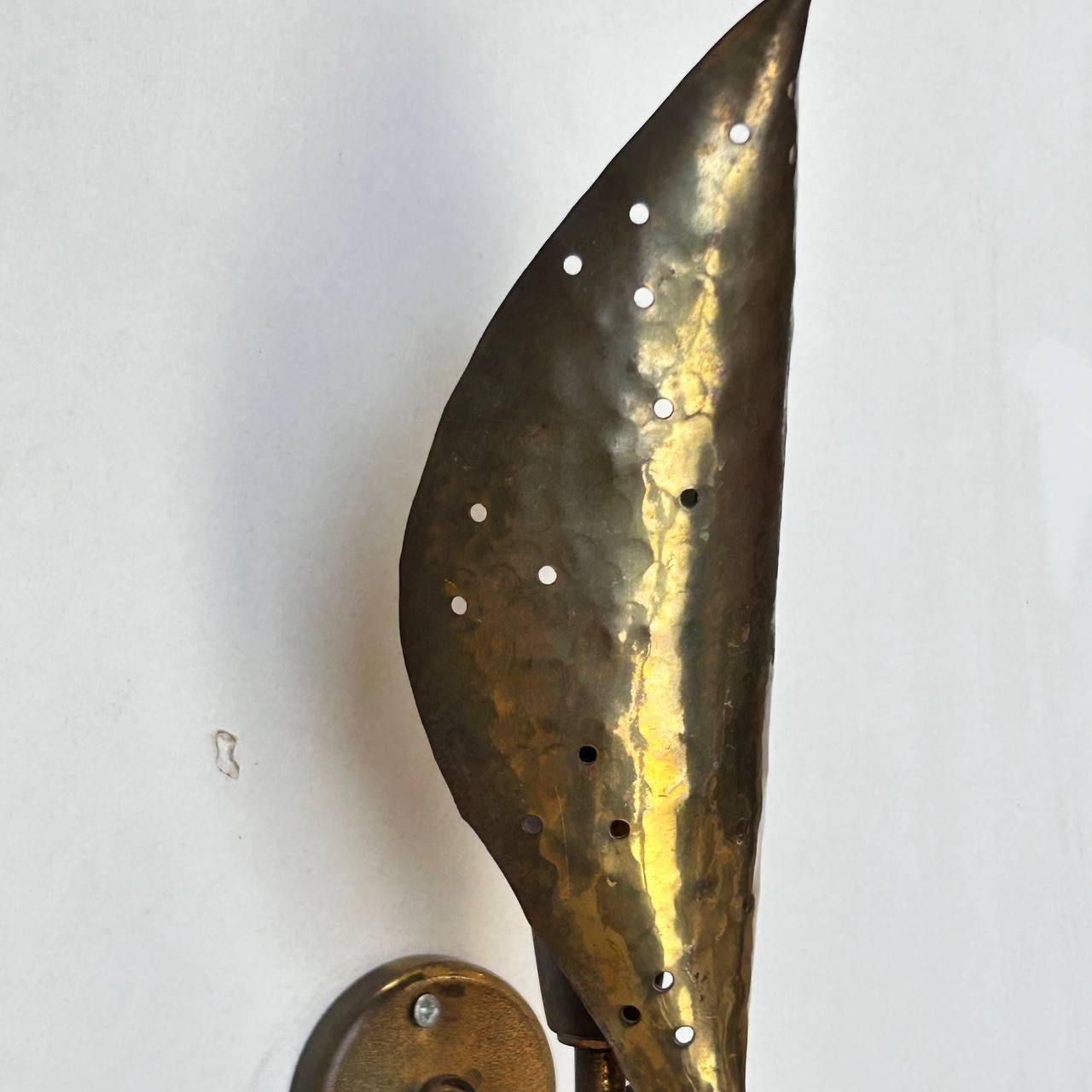 Pair of wall sconces by Angelo Lelii for Arredoluce. Designed and manufactured in Italy, circa the 1950s. Brass leaf-shaped lampshades with hammered details and holes that create exceptional play of light. The brass has a beautiful patina that gives