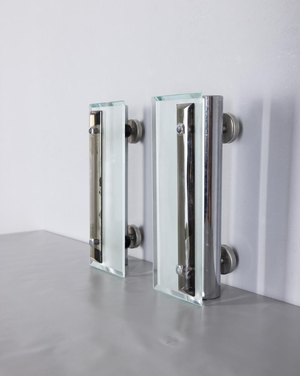 Coppia di lampade da parete con struttura in metallo cromato e vetri trasparenti e fumè, design Italiano, anni 60.

CONDIZIONI:
In buone condizioni, funzionante, possono presentare segni d'usura dati dal tempo.

DIMENSIONI: 
Altezza 21 cm; Larghezza