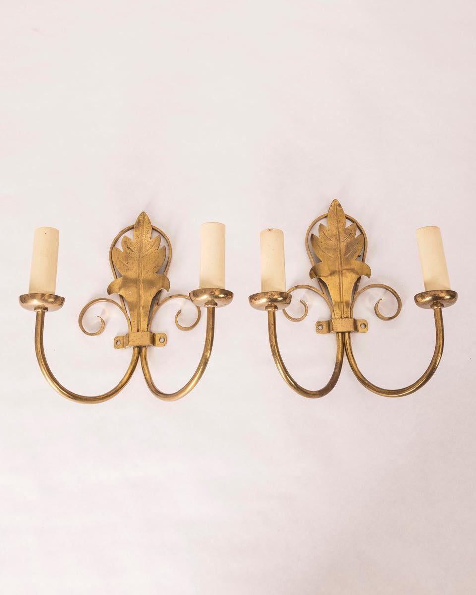 Pair of two-armed gilt brass wall lamps with white wooden lamp holder, 1960s.

CONDITION: In good, working condition, may show signs of wear given by time.

DIMENSIONS: Height 25 cm; Width 22 cm; Length 11 cm

MATERIAL: Brass and Wood

YEAR OF