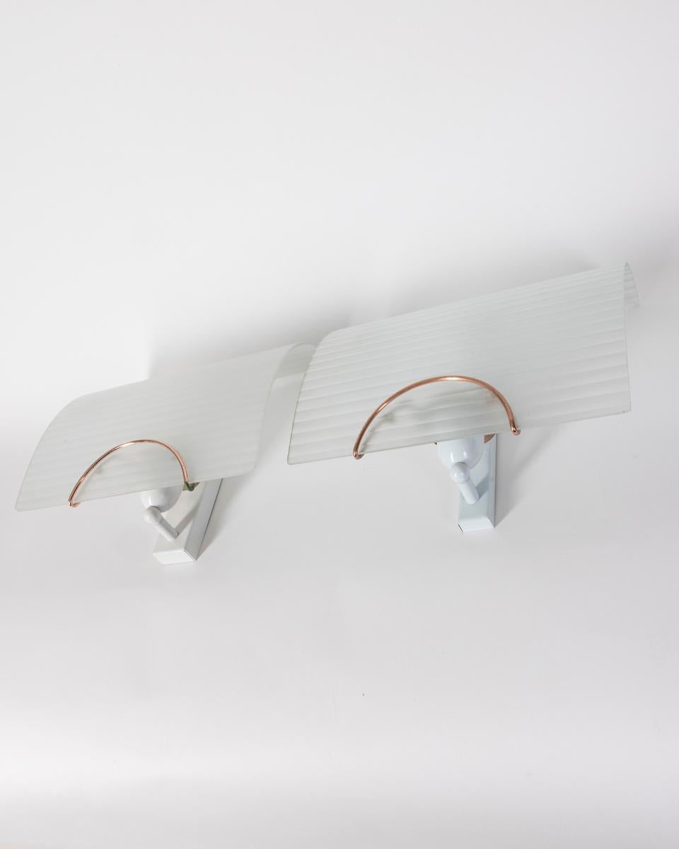 Paar Wandlampen mit vergoldetem Metallrahmen und verzierten Glasschirmen. Eine Lampe hat einen polierten Schirm, die andere einen satinierten Schirm. Italienisches Design, 1980er Jahre.

ZUSTAND:
In gutem, funktionsfähigem Zustand, kann zeitbedingte