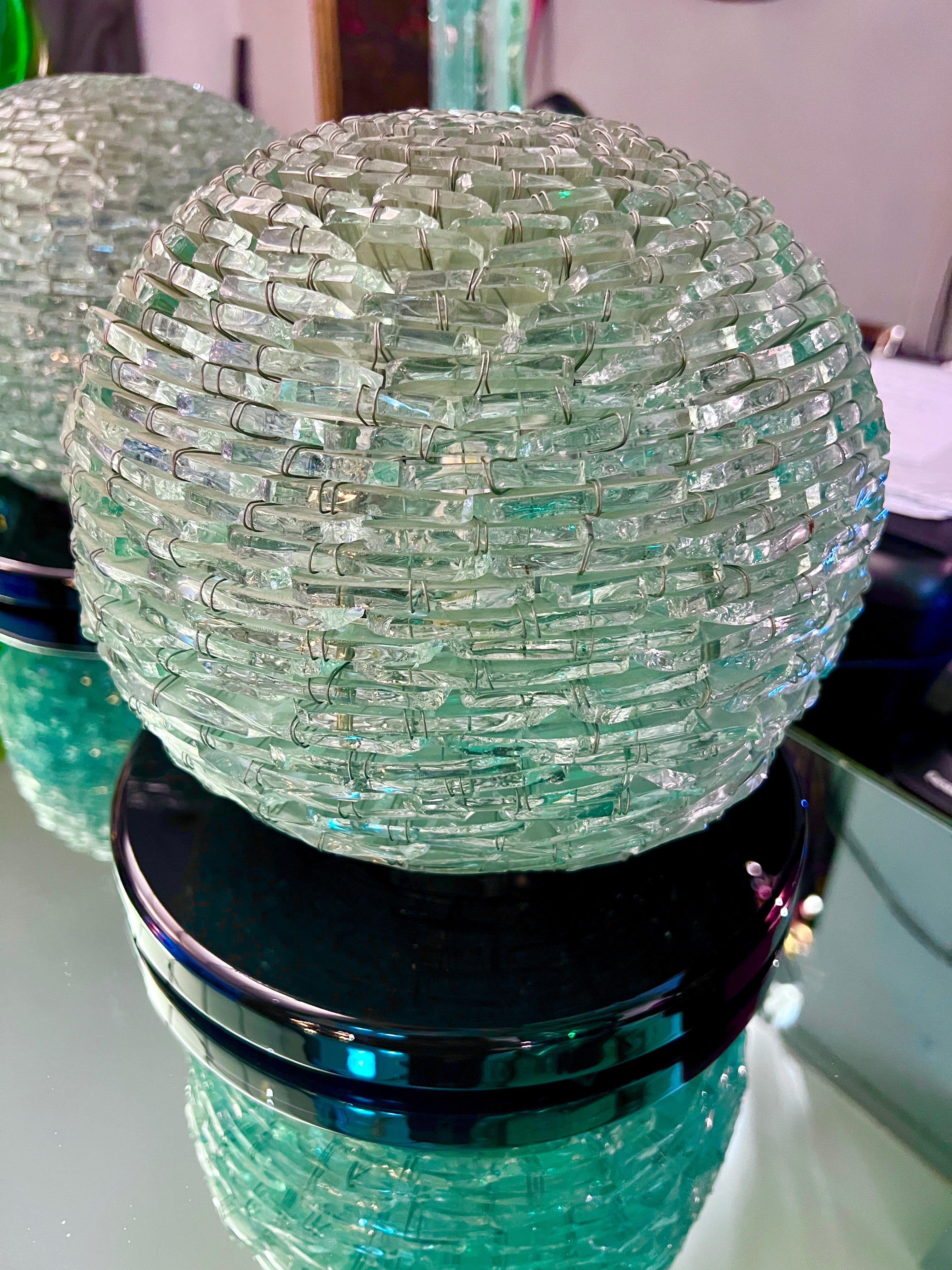 Coppia di lampade sferiche con scaglie in vetro di Murano acquamarina e base in plexiglass nero.
Una lampadina per lampada.