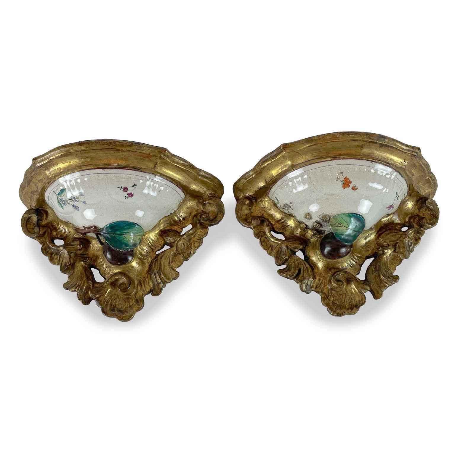 Due Mensole Antiche Dorate italiane del XIX secolo centrate da Maiolica del 1700, piccole mensole sagomate in legno intagliato e dorato, realizzate con un coperchio in maiolica policroma diviso in due parti di una zuppiera antica prodotta da una