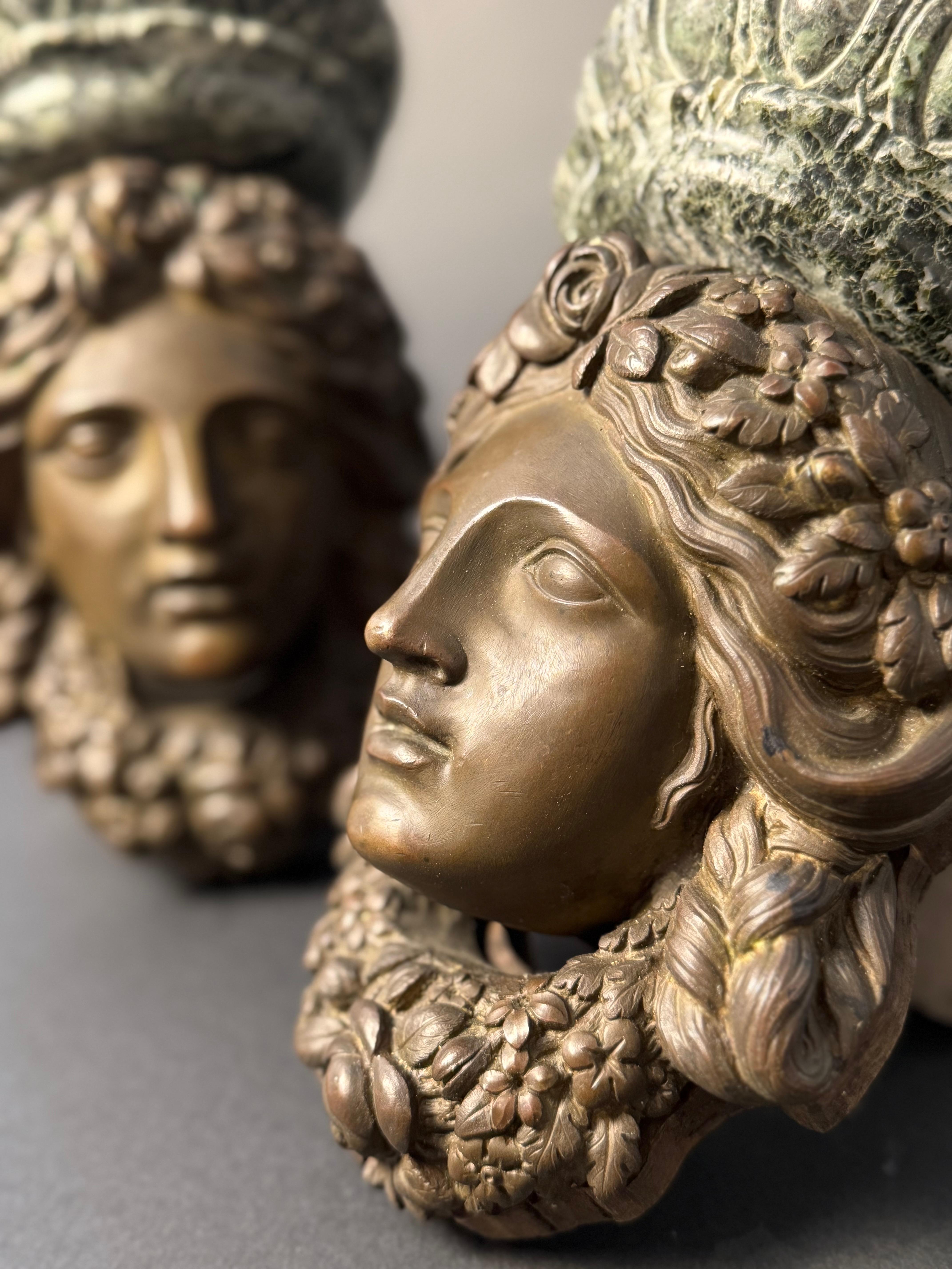 Coppia di mensoline decorative in bronzo e marmo Verde Alpi della prima metà del XIX secolo. Le mensoline presentano il volto di una figura femminile, probabilmente una dea o una musa della mitologia classica, con capelli ricci raccolti e