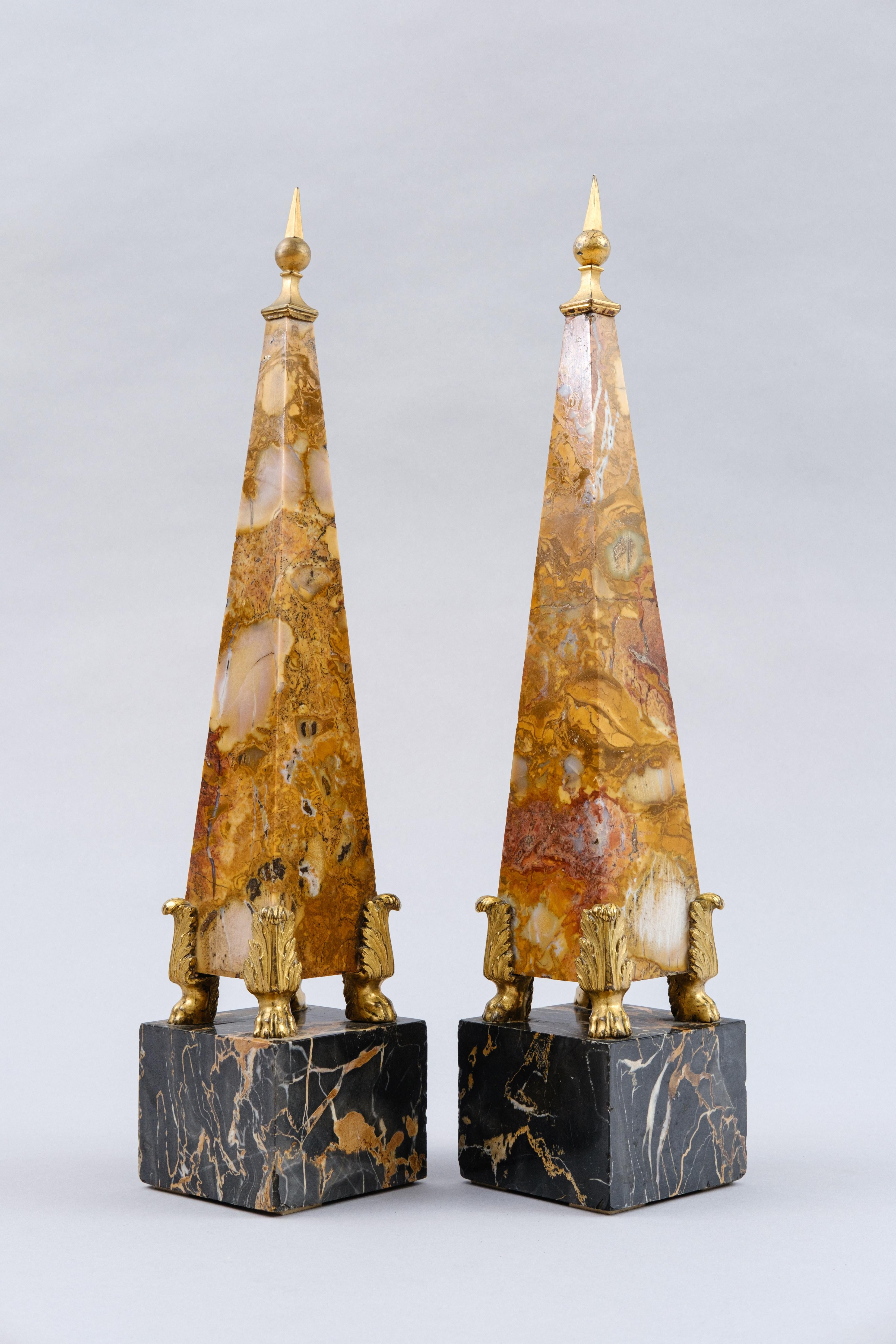 Dieses Obeliskenpaar ist ein elegantes und raffiniertes Beispiel für dekorative Kunst. Die Stücke kombinieren die Verwendung kostbarer Materialien wie Jaspis, Portoro-Marmor und vergoldete Bronze. Dieses Obeliskenpaar folgt dem Geschmack der Grand