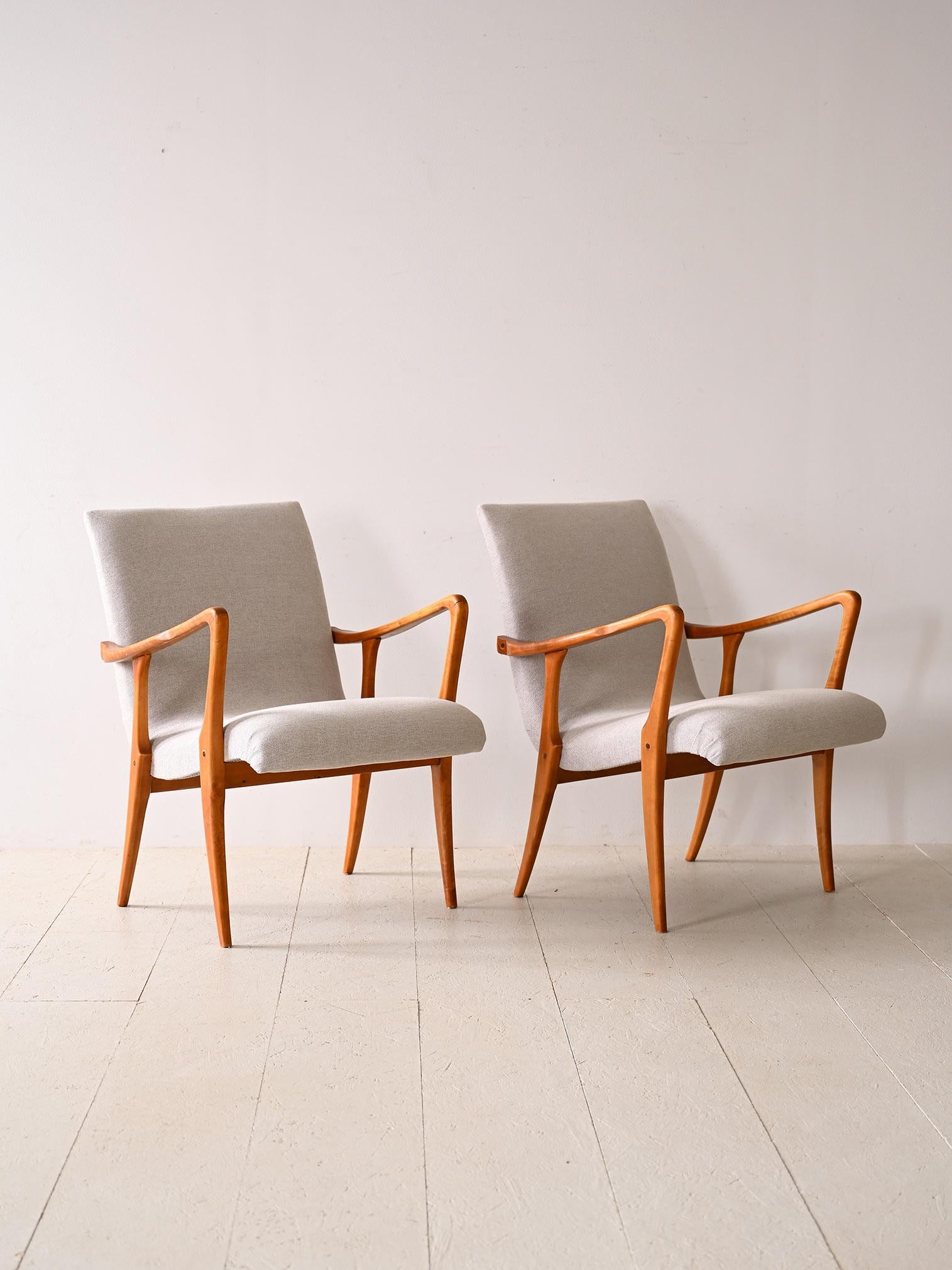 Vintage Scandinavian armchairs made of wood and light-colored fabric. Characterized by a wooden frame that features flowing, harmonious curves that perfectly complement the upholstered seat covered in light-colored fabric. This bright fabric adds