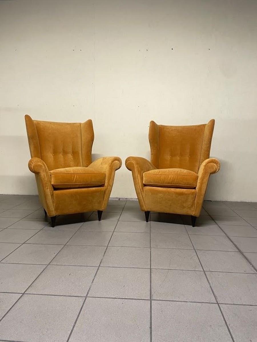 Pair of 1940s armchairs with ebonized wood cone feet and ochre-hued velvet-like fabric.

The armchairs have been completely restored, and this not only enhances their clean and elegant lines but also provides great seating comfort.

Small size and