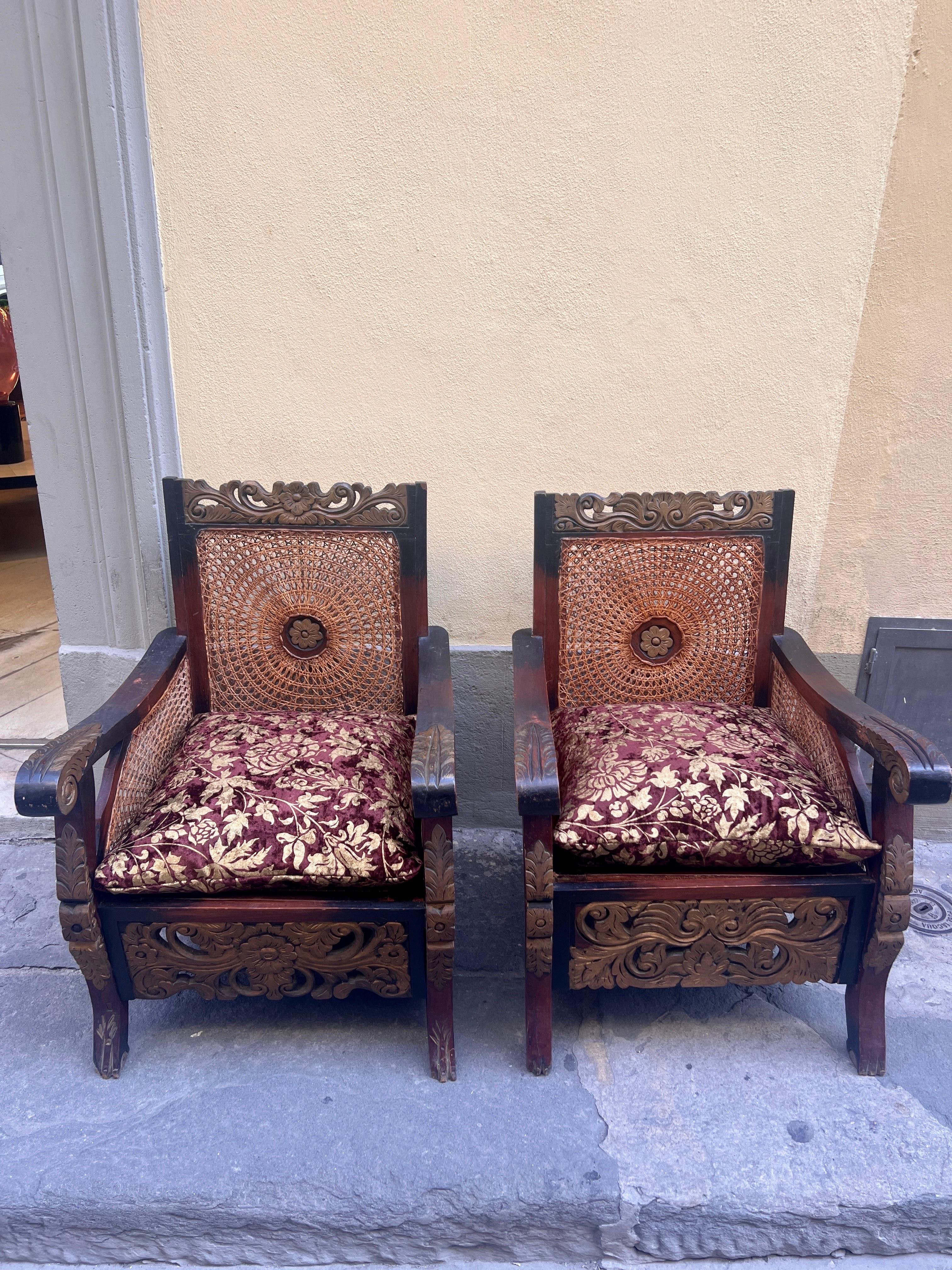 Coppia di Poltrone Coloniali in Legno Intagliato e Doppia Paglia di Vienna, presentate con cuscini in velluto floreale con toni marrone/oro.

