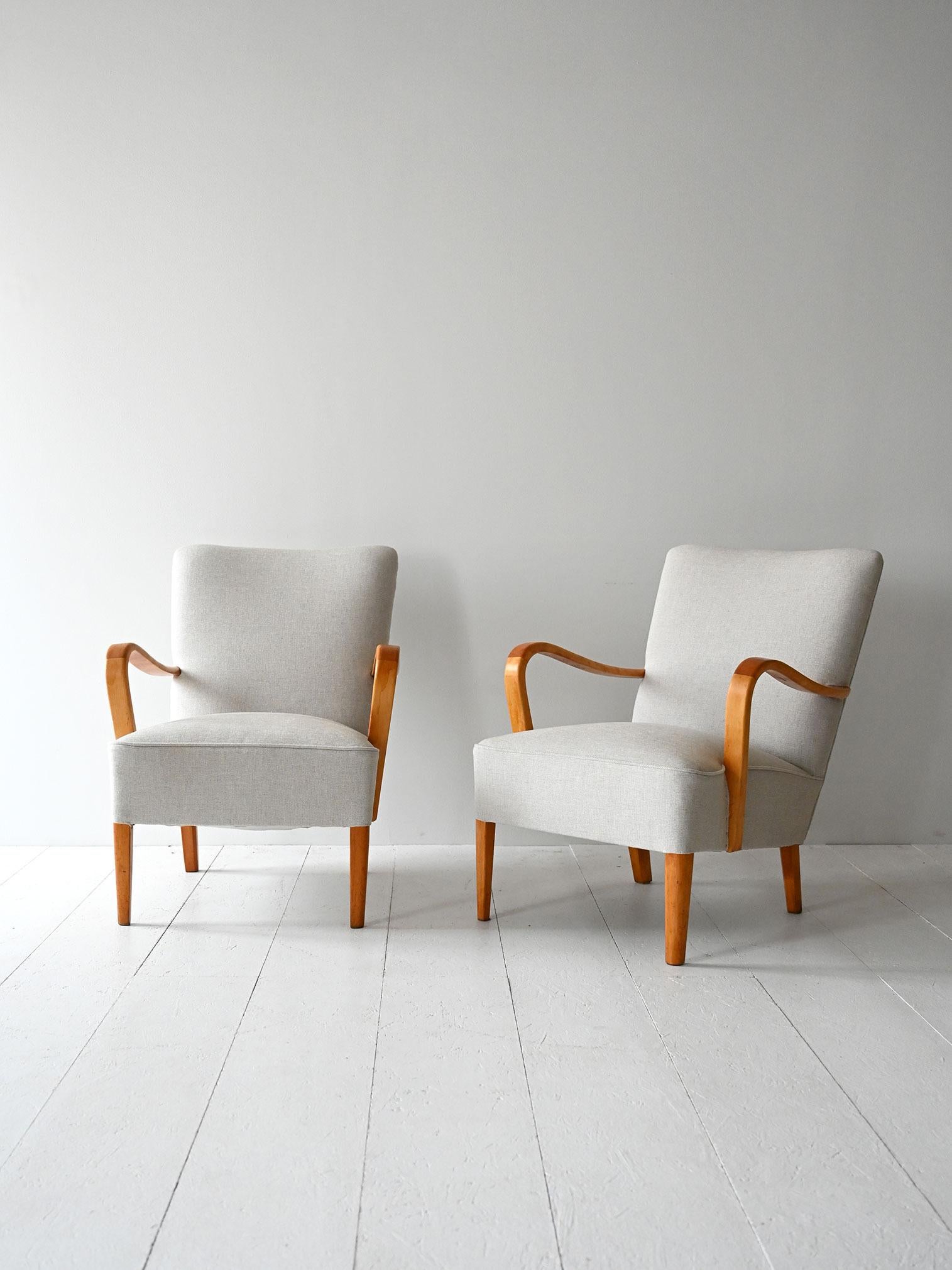 Vintage teak armchairs with curved arms, handcrafted upholstery and cover in light fabric.

Pair of Scandinavian armchairs dating from the 1950s, with teak frame and carved curved armrests. The light-colored fabric upholstery and interior padding