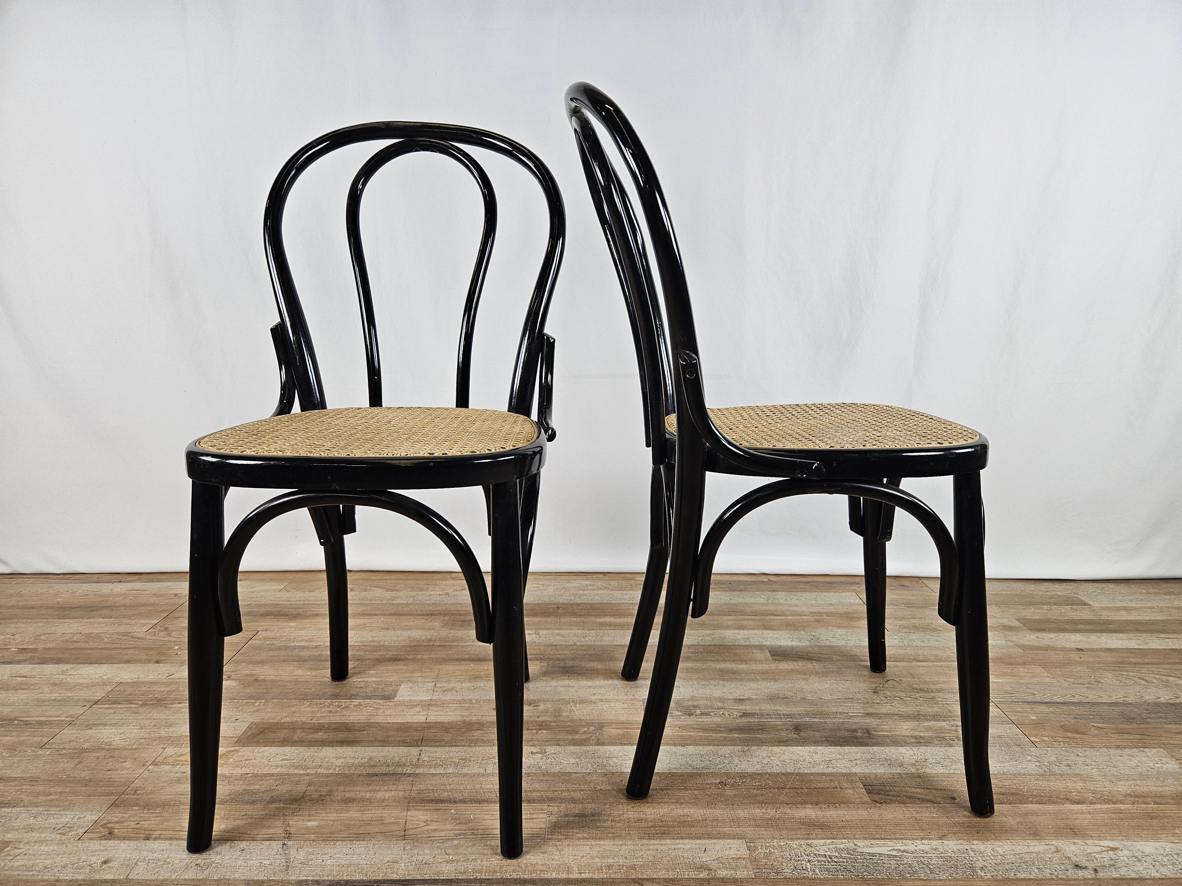 Paire de chaises en bois laqué noir avec assise en paille de Vienne et nœud décoratif entre le dossier et l'assise.

Idéal pour les cuisines, les bureaux, les salons ou comme éléments de mobilier.

Signes normaux dus à l'âge et à l'utilisation.