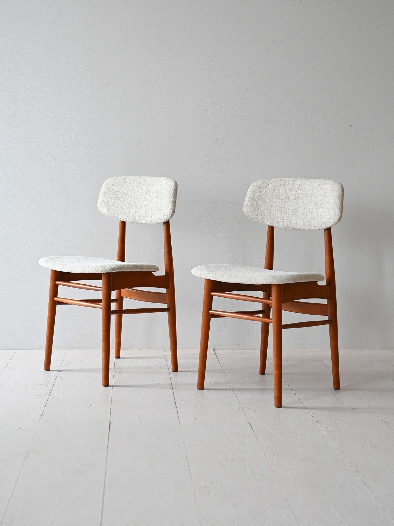 Set of two original vintage Scandinavian chairs with wooden frame and upholstered seat and back. 

The light-colored upholstery fabric also makes them suitable for contemporary environments. The soft lines and conical legs hint at organic design. 