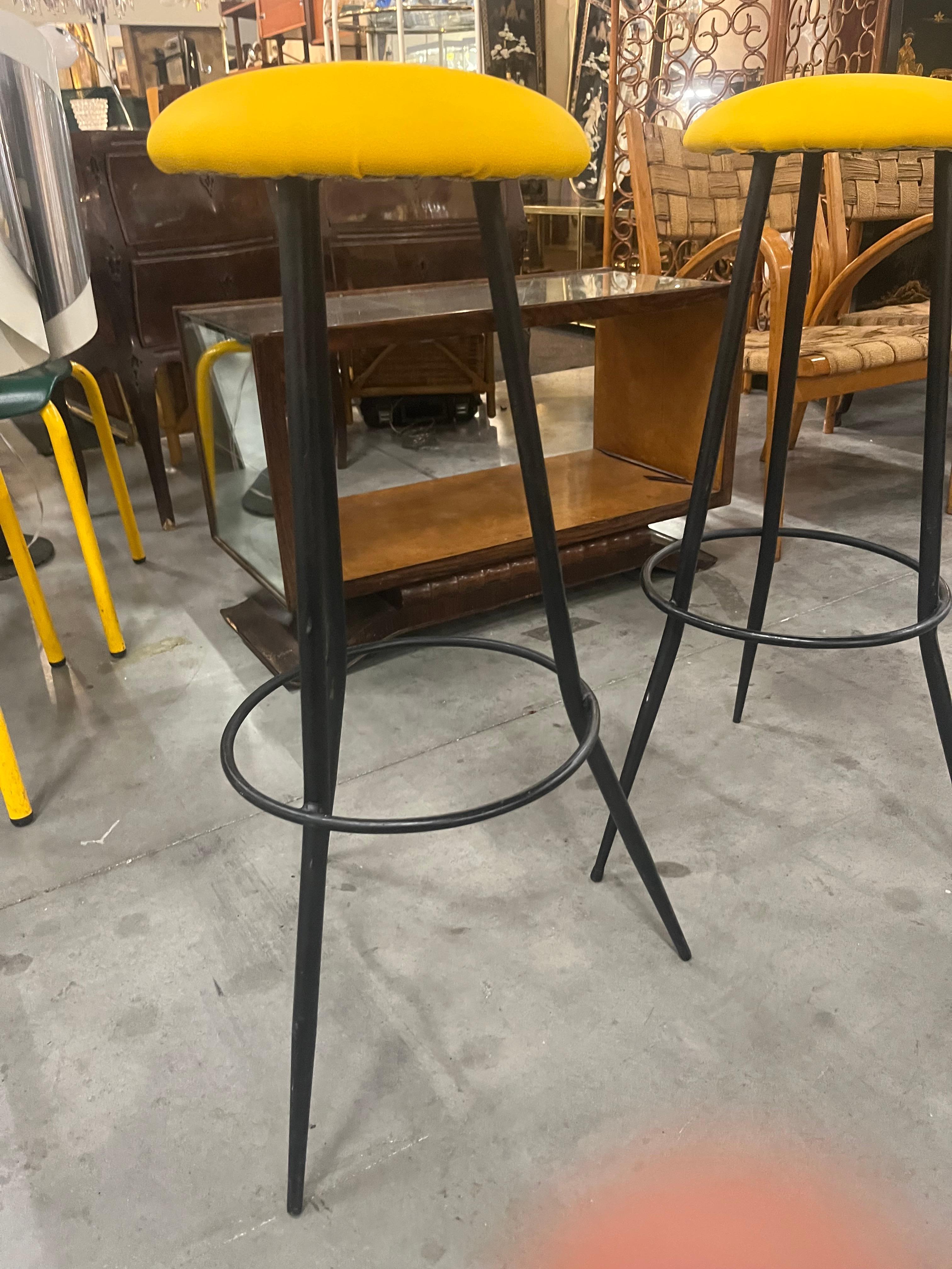 Paire de tabourets de bar des années 1970 avec structure en fer à trois pieds 
et siège en similicuir jaune ciel.
la session a été récemment reprogrammée.
Les tabourets mesurent 73 cm de hauteur et 28 cm de diamètre au niveau de l'assise.
