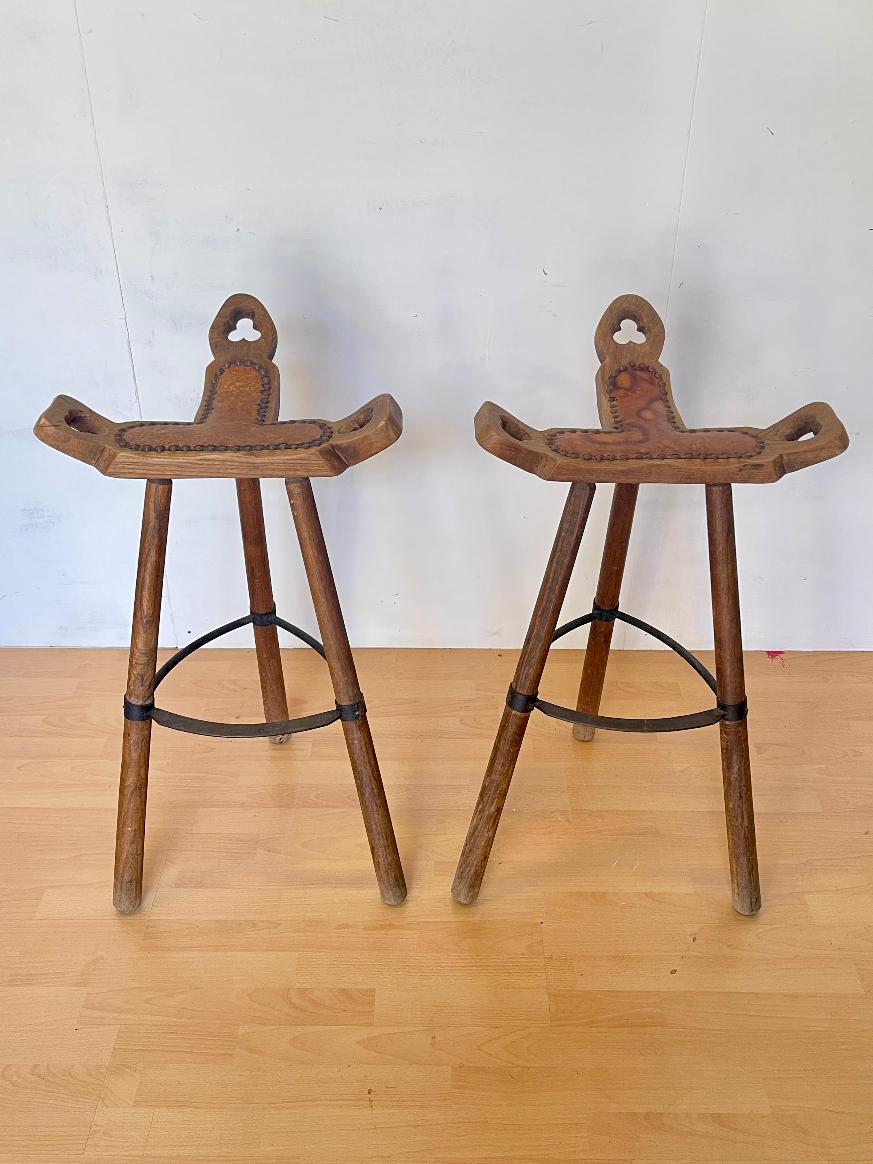 Charmante paire de tabourets hauts en bois massif fabriqués à la main, au caractère rustique et authentique, parfaits pour les décors alpins, campagnards ou les chalets de montagne. L'assise sculptée à la main avec des détails ornementaux et le
