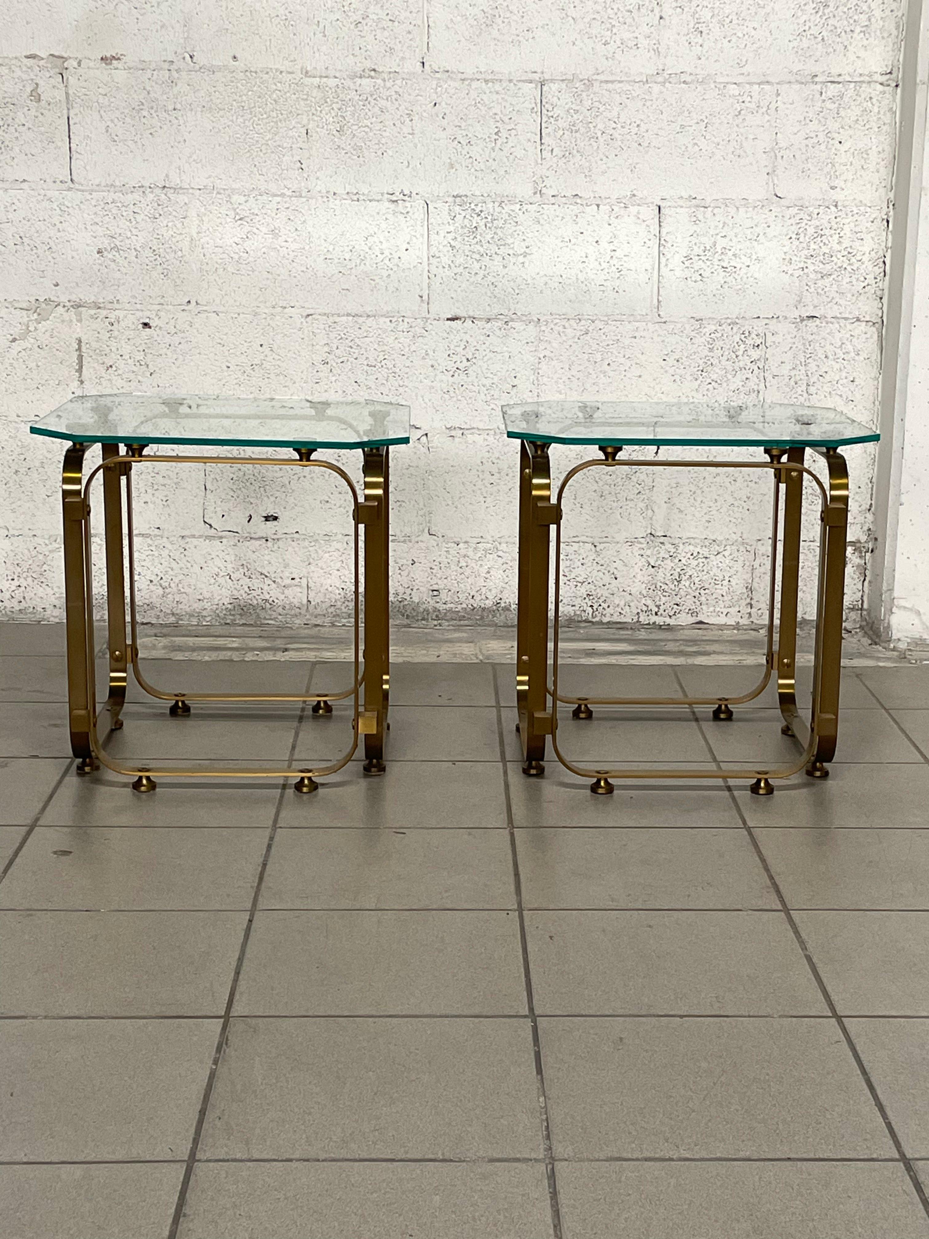 Pair of 1970s coffee tables made of brass and shaped polished glass top.

The pair in addition to being used as side tables can also be used as bedside tables.

The pair is in excellent condition.
