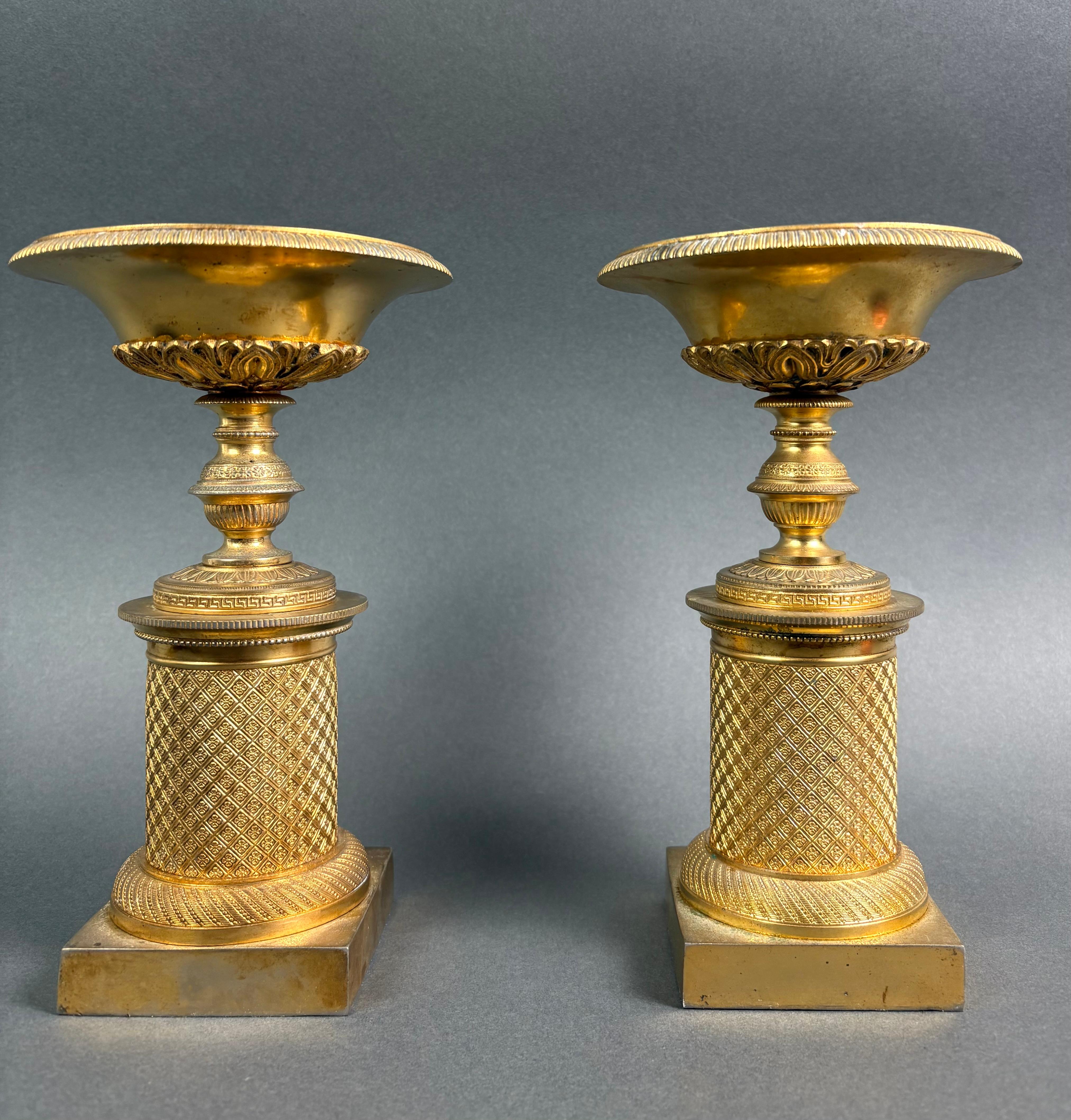 Paire de bassins en bronze doré au mercure d'époque Empire, vers 1810. 
Les deux bassins sont montés sur une colonne cylindrique reposant sur un socle, richement décorée de motifs typiques du goût de l'Empire, tels que des petites fleurs et des