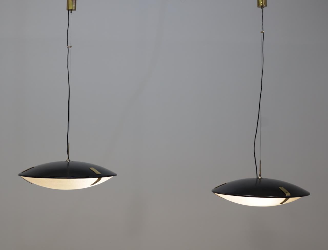 Pair of Stilnovo Model 1140 Adjustable Suspension Lamps1 Stilnovo with black enameled aluminum shade that suspends textured glass dome shade with brass fittings and suspended from original brass canopy with custom ceiling plate.
Questo modello