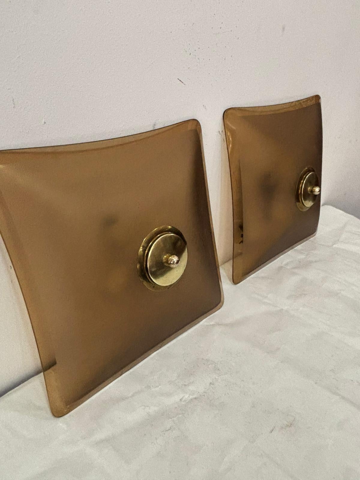 Coppia di applique da incasso o da parete in vetro color fumé satinato con bordo smussato e con supporti in ottone su piastra bianca di produzione Italiana degli anni '60 nello stile di Fontana Arte.
