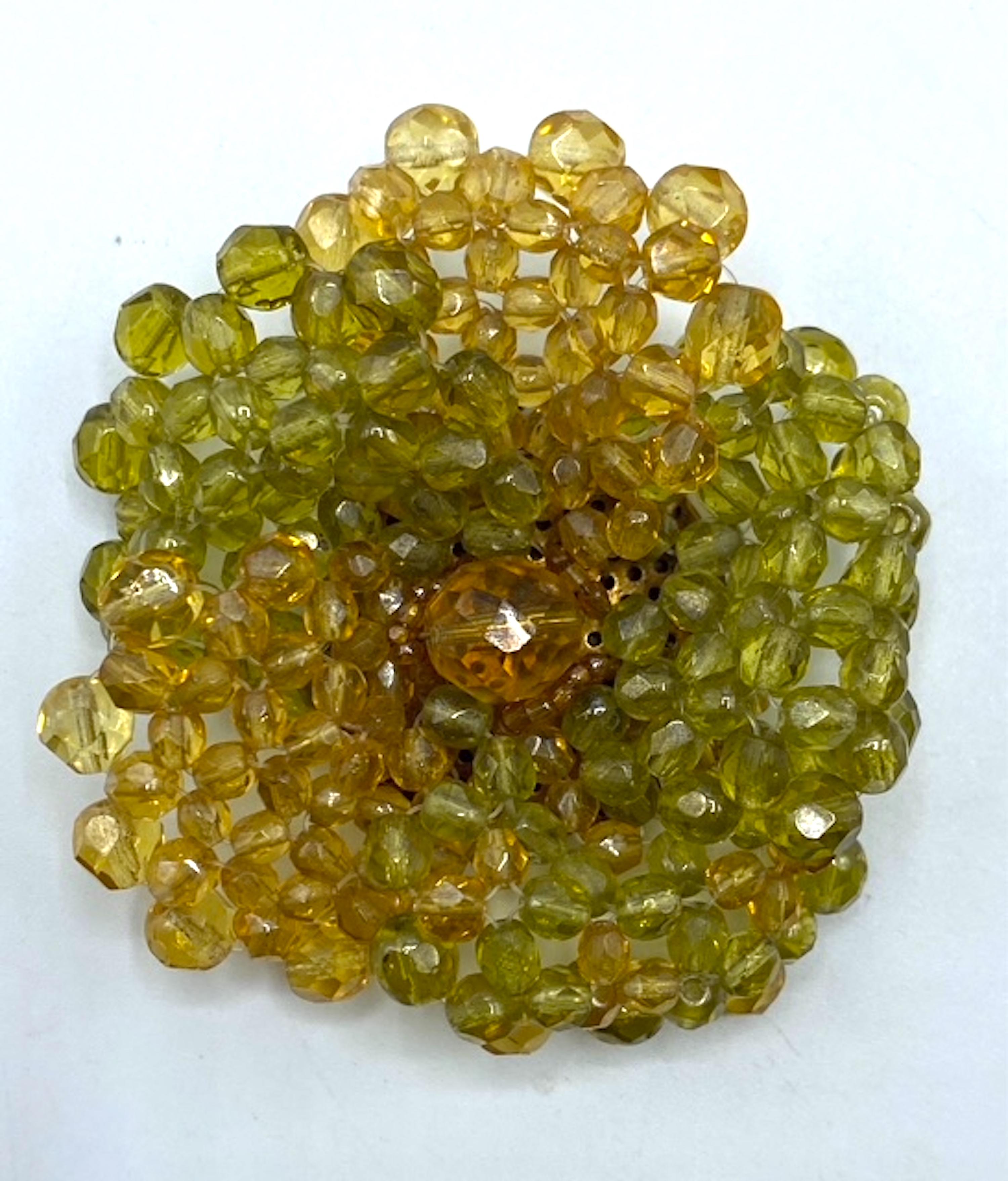 The 1960s two tone light olive green and pale amber crystal bead flower brooch by Coppola e Toppo is a prime example of the intricate craftsmanship and distinctive design style the company is known for. Bruno and Lyda Coppola began their fashion