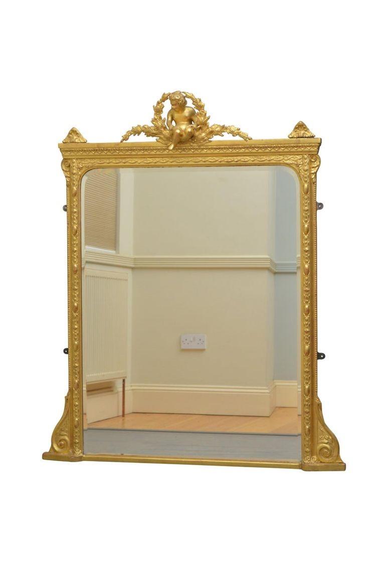 K0403 Miroir mural en bois doré de style victorien avec verre biseauté d'origine (avec de petites bulles d'air) dans des cadres sculptés avec un chérubin au centre et de fines volutes à la base. Ce miroir a conservé son verre et sa dorure d'origine,
