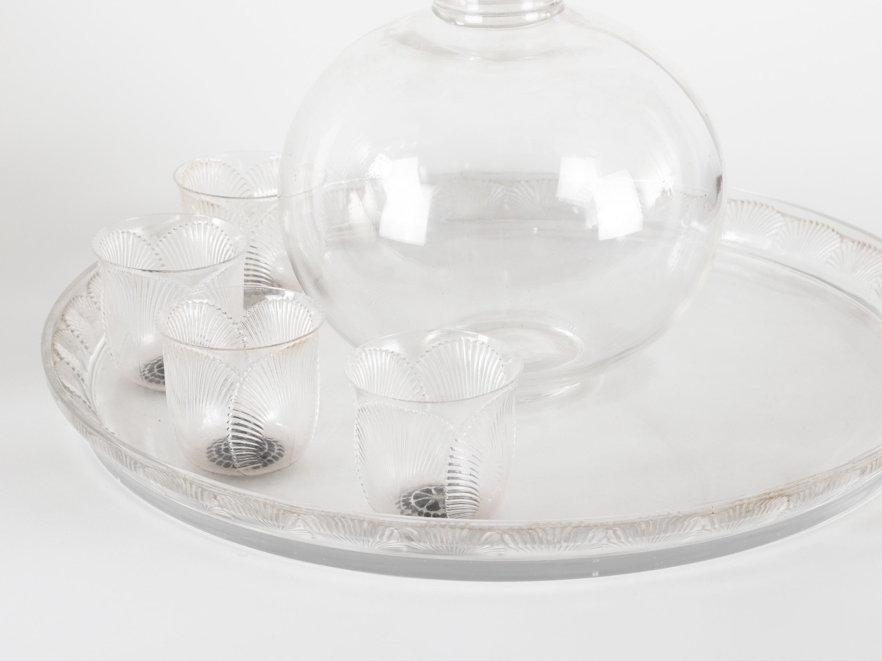 Un servicio de bebidas Coquelicot de René Lalique, una auténtica joya de los años 30.

Este precioso conjunto está fabricado en vidrio soplado blanco, con una impresionante combinación de acabados transparente y esmerilado. Los intrincados motivos