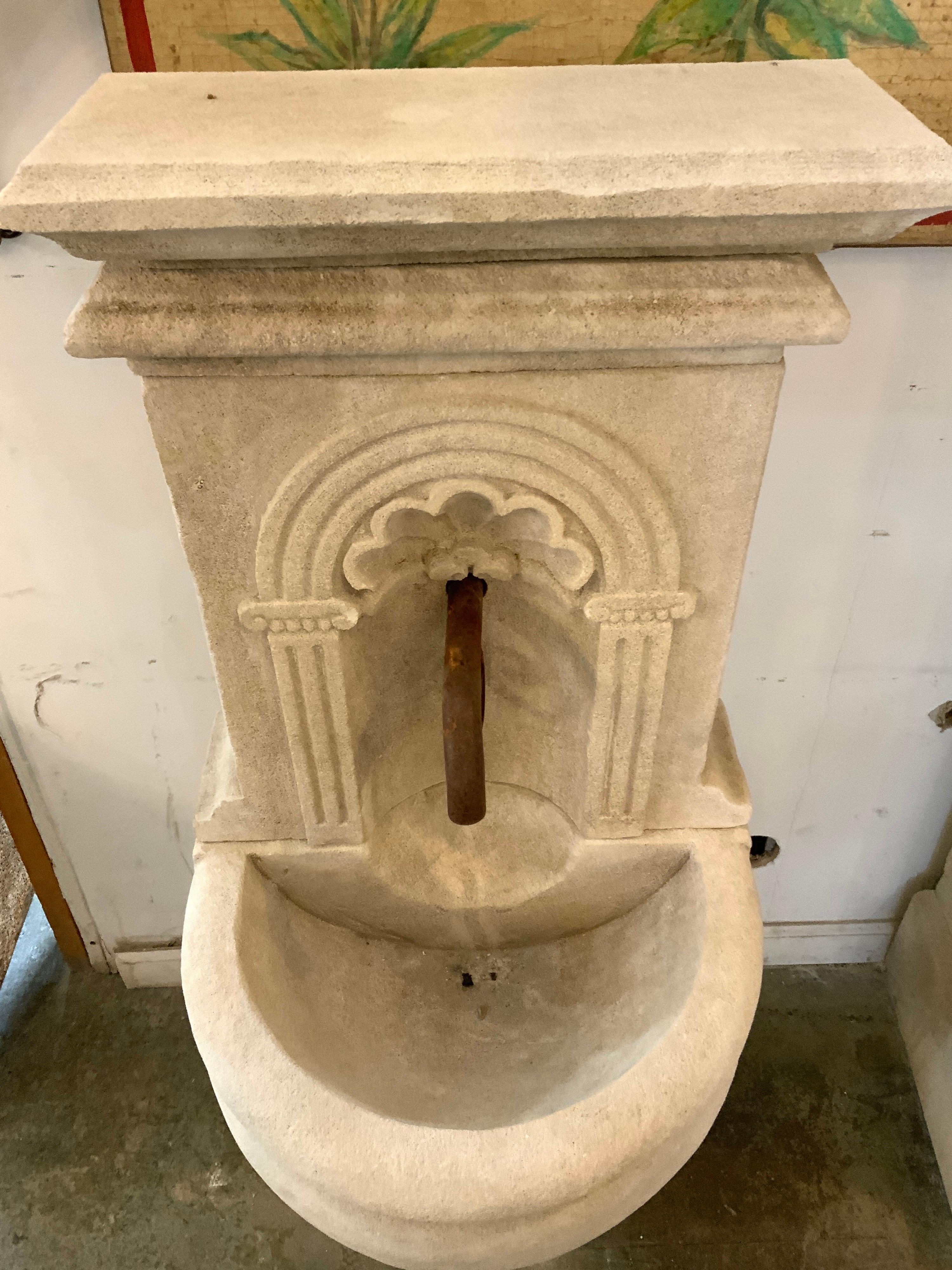 Voici une fontaine murale en pierre calcaire sculptée à la main en provenance de France, avec un motif de coquillage et un bassin semi-circulaire sur un support. Semblable à la fontaine 