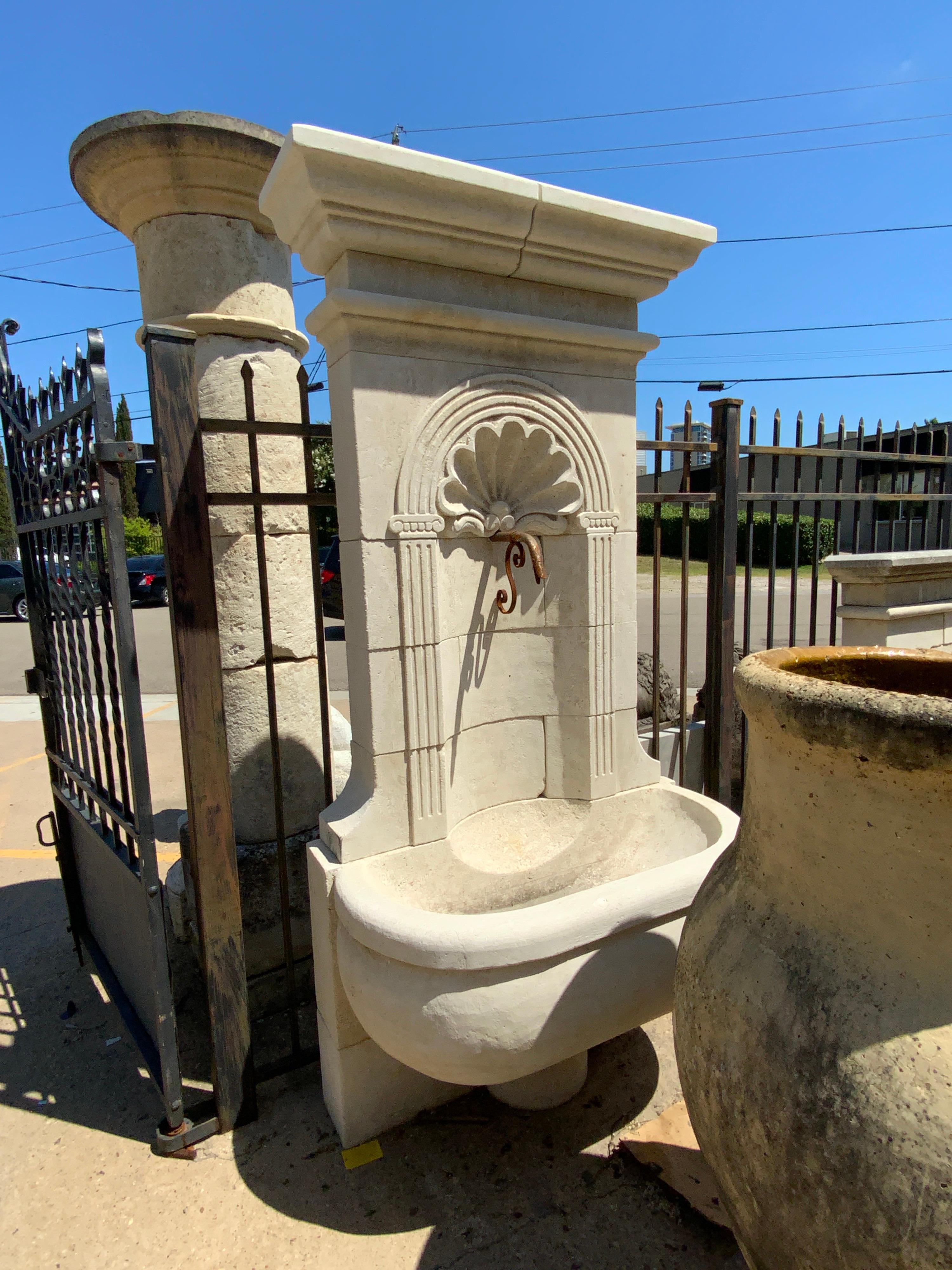 Here we have a hand carved limestone wall fountain from France with a shell design and semi-circular basin on a stand. Similar to out 