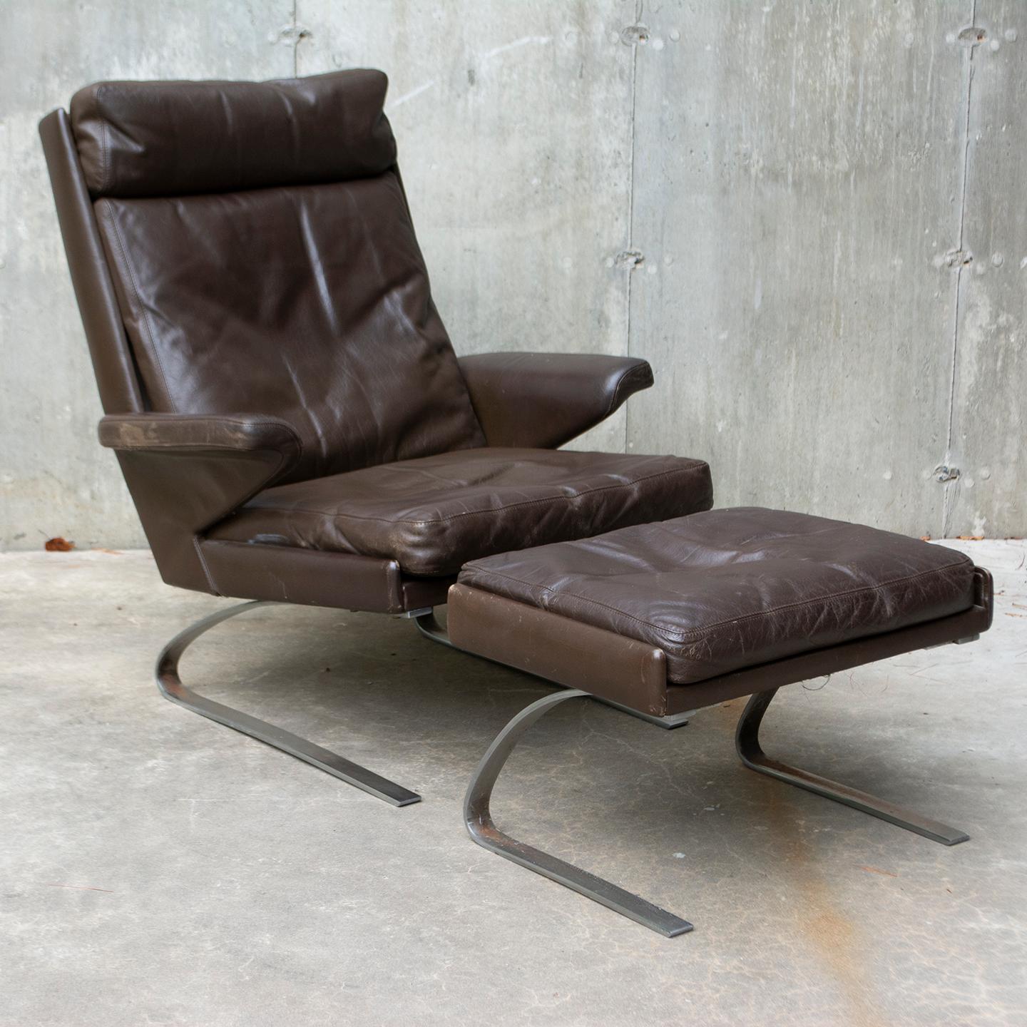 Swing lounge chair with ottoman designed by Reinhold Adolf and Hans-Jürgen Schröpfer for COR Germany. This set has a brushed steel frame and comes in its original dark brown leather patinated by age and use. Some areas show more wear and fade but