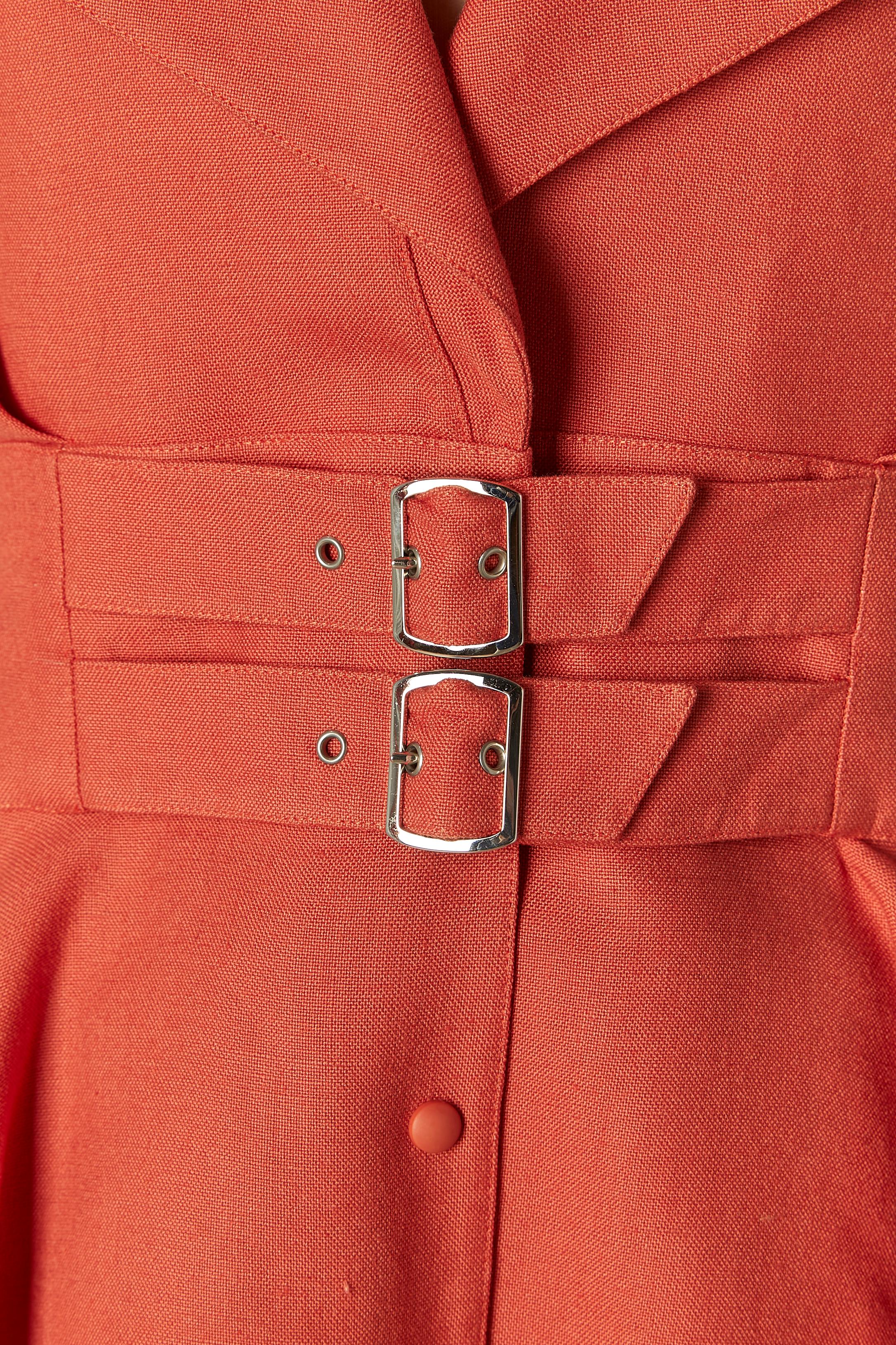 Gonna-suit in rayon e lino Corail. Composizione del tessuto: 80% rayon, 20% lino. 
Chiusura a scatto sul centro della parte anteriore. Cintura corta e fibbia in metallo argentato al centro della vita. Spallaccio. Un seno in alto a sinistra.
TAGLIA
