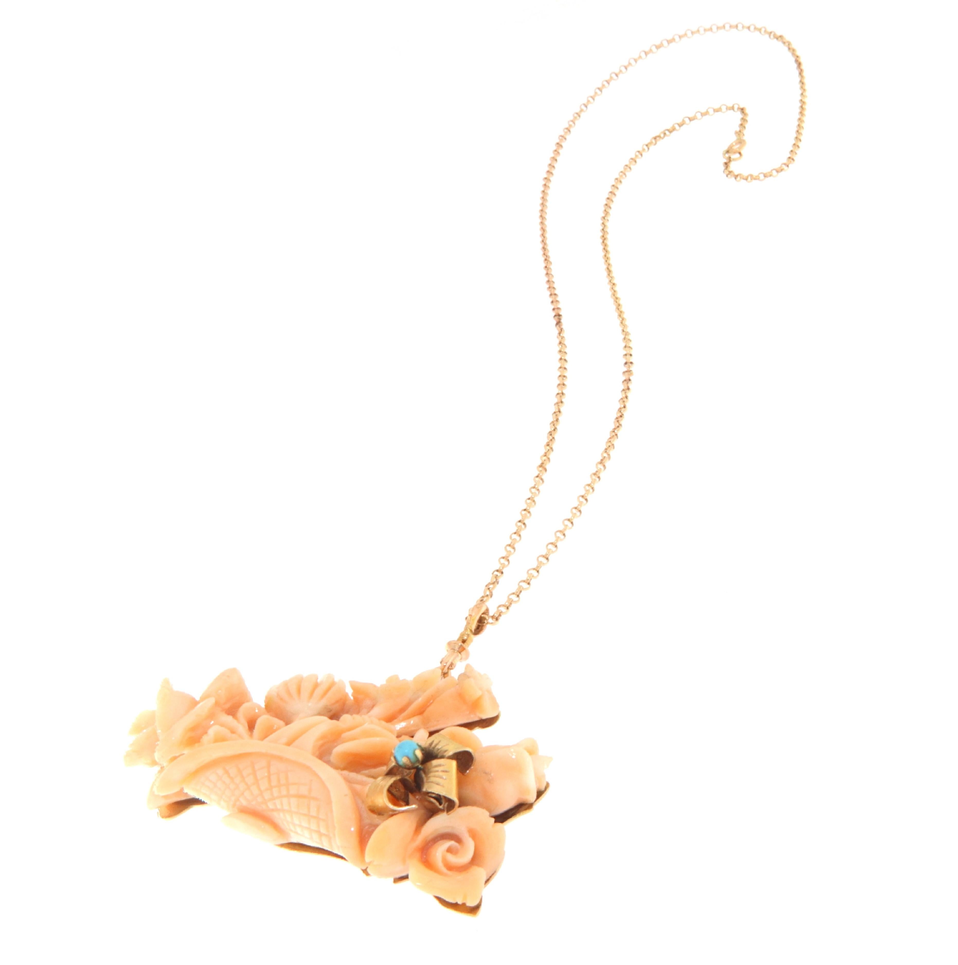 This exquisite necklace, crafted in 14-karat yellow gold, features a central piece of coral, intricately carved into a delicate bouquet of flowers and foliage, displaying the natural beauty and depth of the coral. A small turquoise stone is