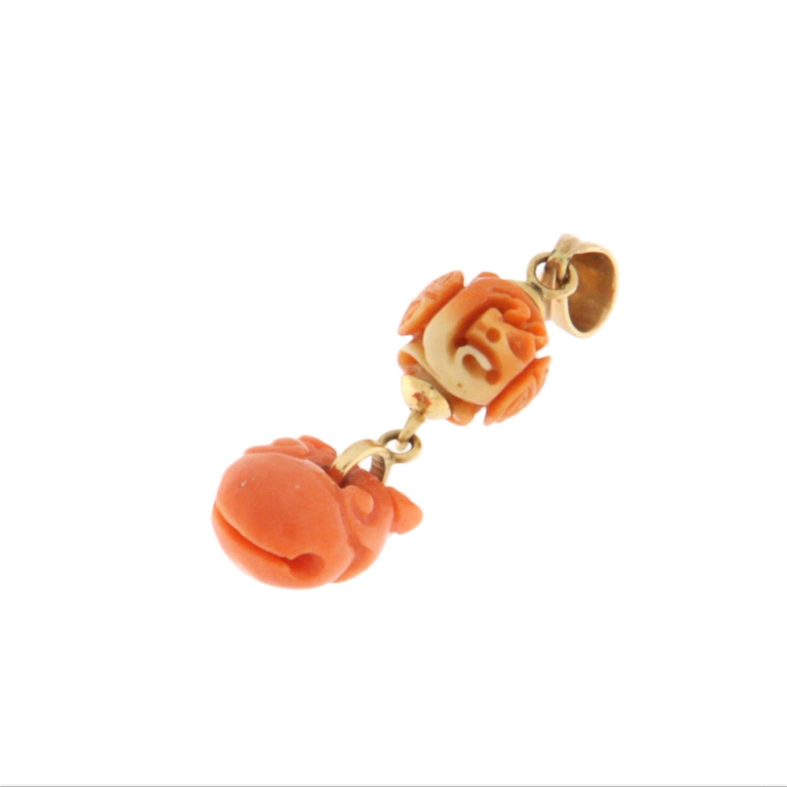 Ce pendentif raffiné en or jaune 14 carats est une pièce unique qui allie charme exotique et savoir-faire traditionnel. Elle comporte deux éléments en corail naturel sculptés à la main. La partie supérieure présente une sphère en corail délicatement