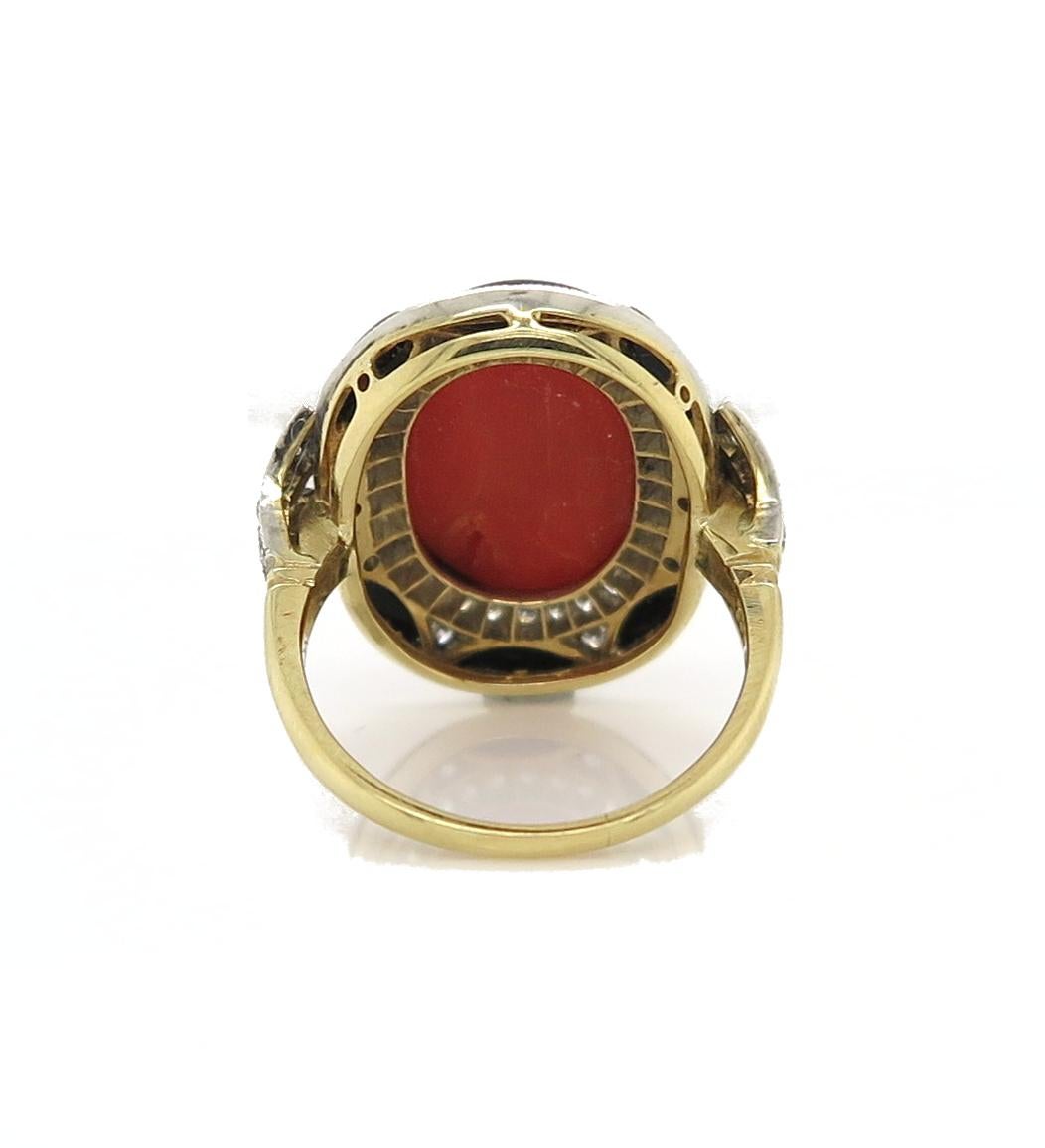 A unique cabochon-cut 9.37 carat Coral stands out in a vibrant red, framed by beautiful Onyx and Diamonds. A total of fifty-six diamonds are showcased surrounding the central stone and the shank, equating to 0.85 carat. Crafted in 18 carat white and