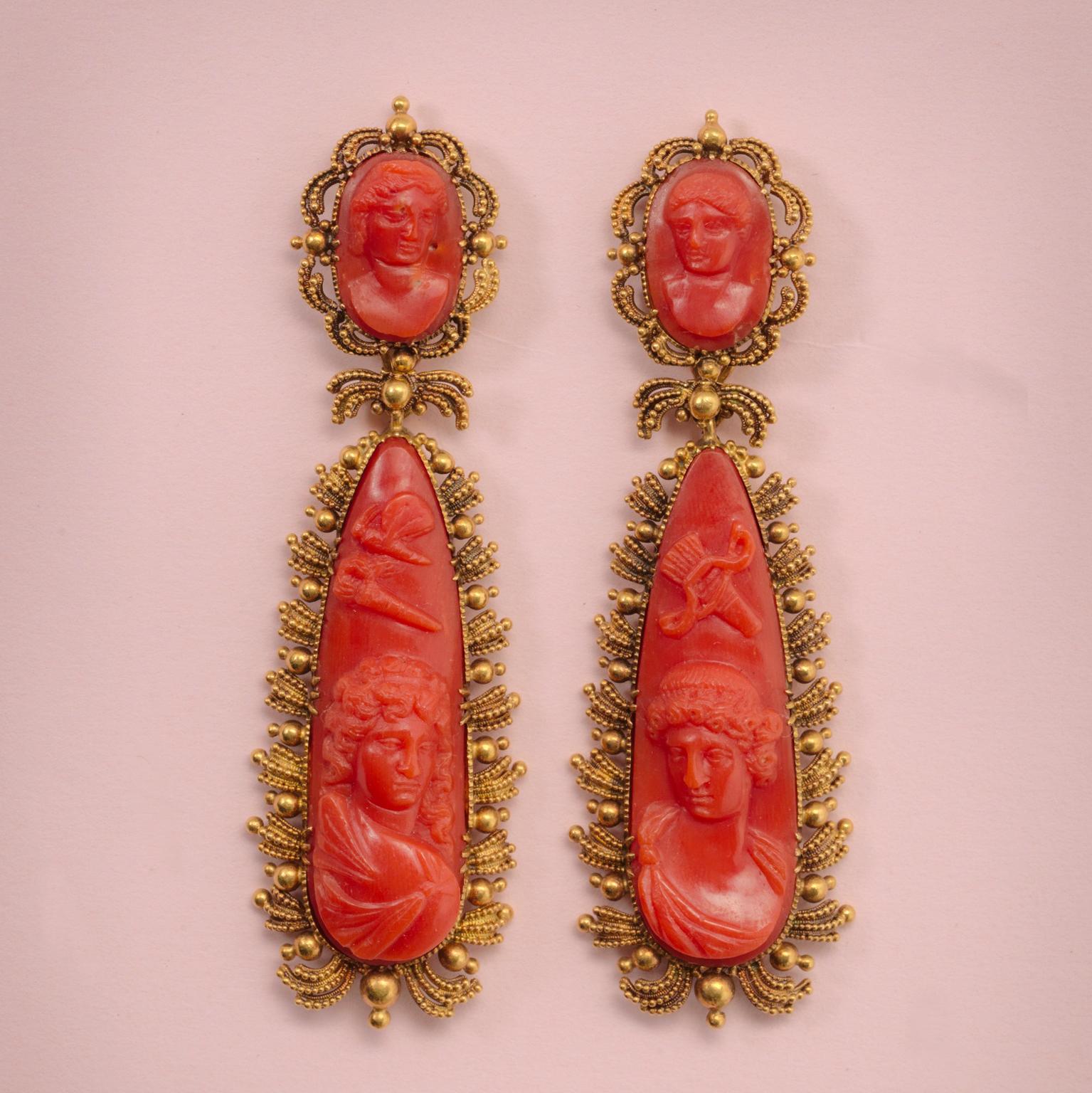 A pair of 15-carat gold and coral - day and night - earrings. The two detachable parts have large, drop-shaped coral cameos. They depict Amor with his bow and arrow and Psyche with a butterfly looking at each other. The smaller oval top parts are