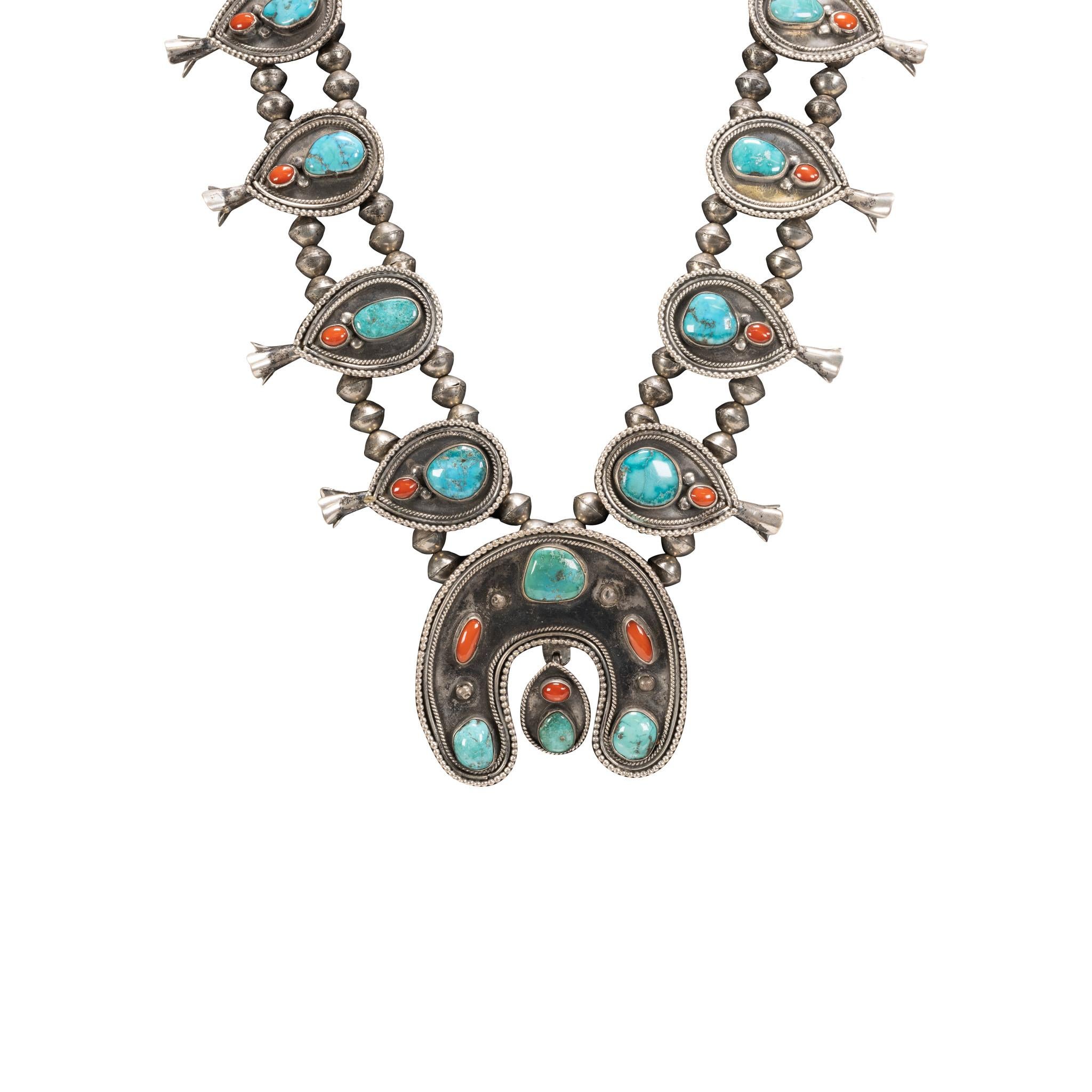 Navajo squash blossom necklace. Ten petals on double strand Navajo pearl chain, featuring a teardrop shape shadowbox with coral and turquoise nuggets inside. Naja has similar design with three turquoise stones, two coral nuggets, and drop. The