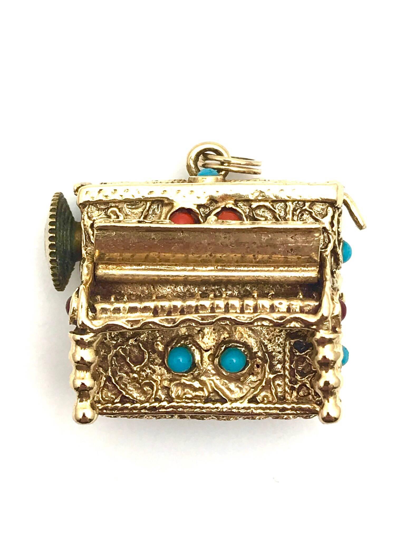  cabochon coral and turquoise 14 karat yellow gold wind up musical piano charm.  The decorative stones are bezel set throughout the charm.  The piano itself has great gold work detail, including the legs, individual keys, and the hinged keyboard