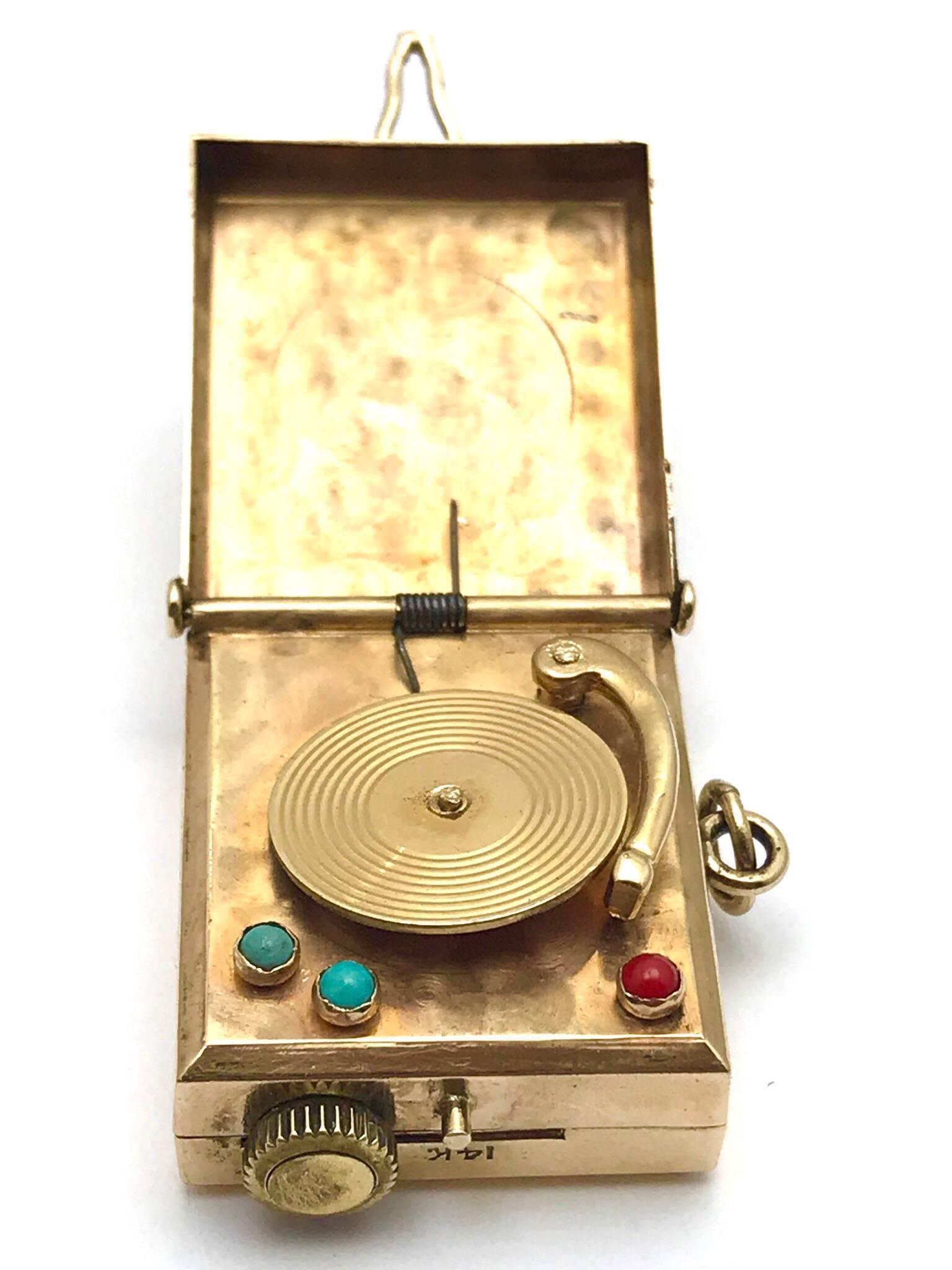  coral and turquoise yellow gold musical Victrola charm.  The decorative stones are bezel set, acting as the power and volume buttons on the record player. The Victrola itself has great gold work detail on the record and the arm.  The case cover is