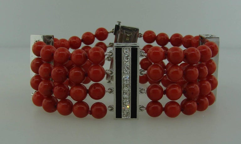 Gorgeous bracelet featuring four-strand Mediterranean coral beads alternating with four white gold bars set with diamonds and accented with black enamel. 
The bracelet is 7