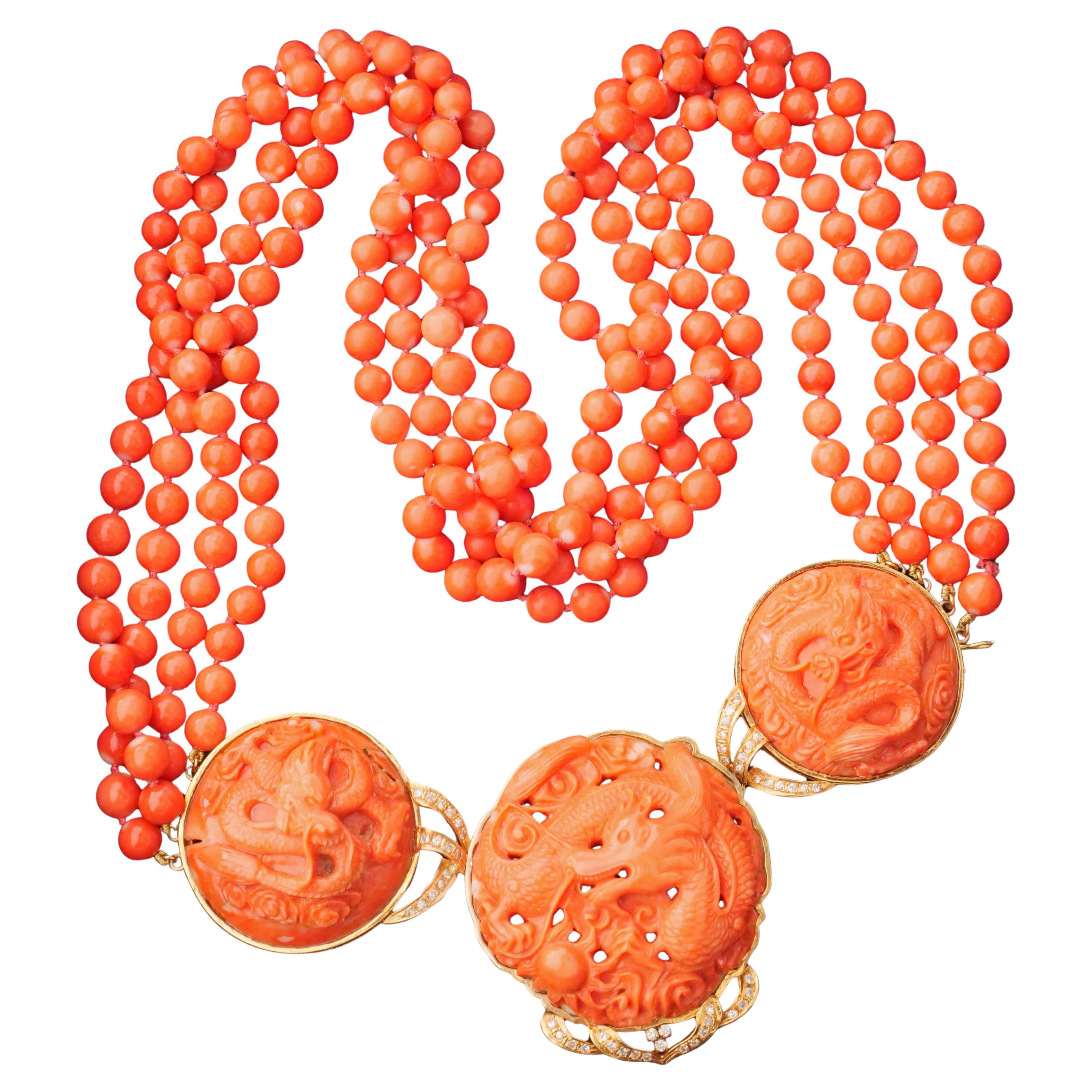 magnifica collana con grandi intagli a forma di draghi nella parte centrale decorativa con diamanti taglio brillante incastonati per un totale di circa 0,75 carati, dimensioni circa 12,2 x 5 x 1,7 cm, sfere di corallo a 4 file di dimensioni 6,5-7