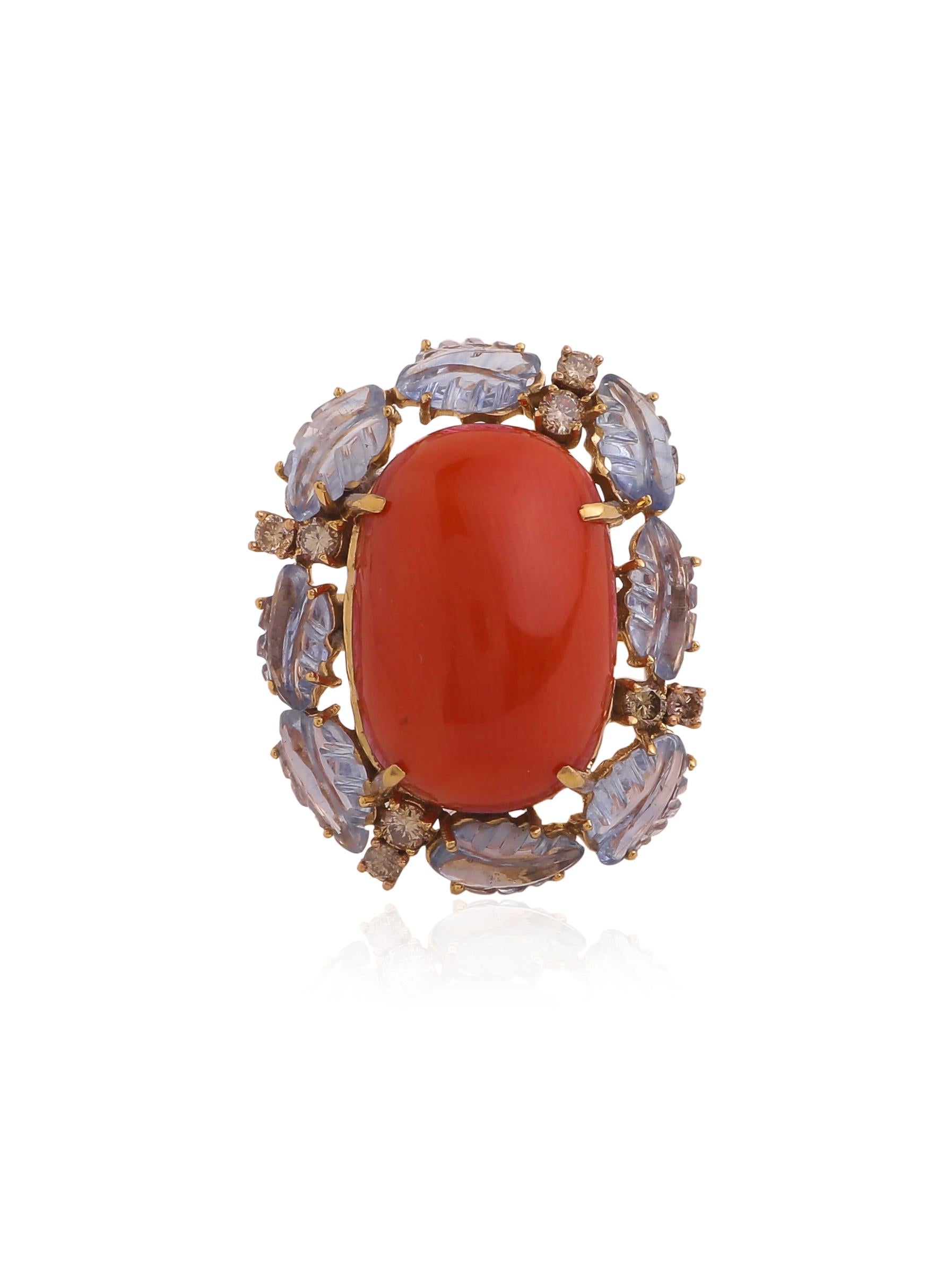 A cocktail ring with a big coral in the centre and a row of sapphire carved leaves and diamonds on the side.
The Coral and the sapphires compliment each other and the brown diamonds blend in yet gives the ring a good shine. 
The ring is inspired