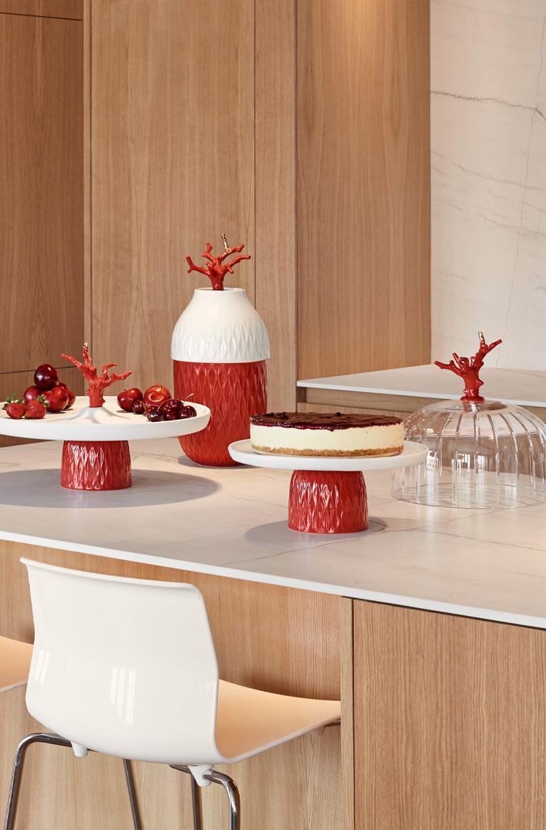 Cake plate from the Coral Collection made in glazed porcelain, decorated in white and red with touches of golden luster. The Coral Collection is inspired by the beauty of coral reefs. It interprets them from two different points of view, combining a