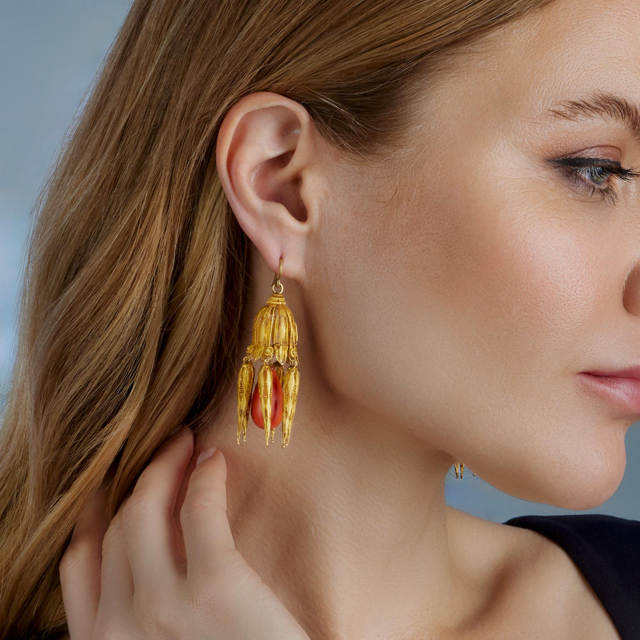 Dating from the early 19th century, these gold cannetille pendant earrings are set with coral. Each pendant earring formed of delicate hand fabricated gold wire is designed as a domed top of pendant leaves, tendrils and tiny rosettes suspending a