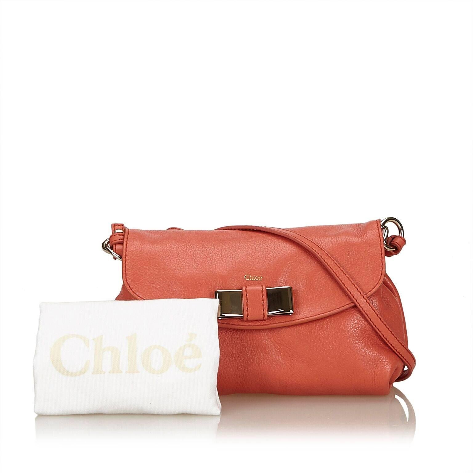 Product details:  Coral leather Lily crossbody bag by Chloe.  Adjustable crossbody strap.  Metal bow accents front flap.  Concealed magnetic snap closure.  Lined interior with inner slide pocket.  Silvertone hardware.  Dust bag included.  8