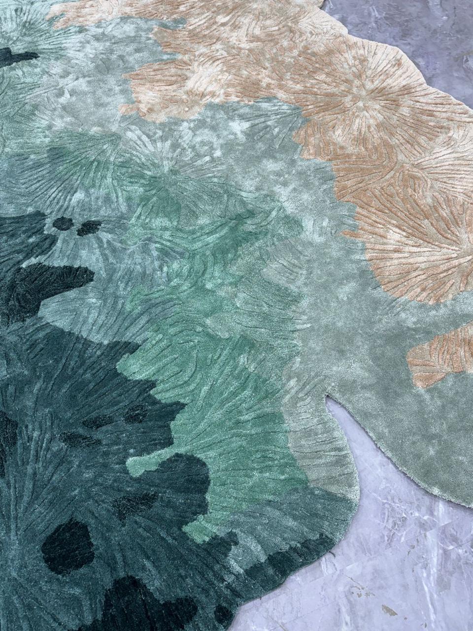 CORAL ist ein skulpturaler Teppich, inspiriert von der filigranen Schönheit und organischen Geometrie von Korallenformationen unter Wasser. Fließende Schichten botanischer Texturen in Jadegrün-, Elfenbein-, Sand- und Meerschaumtönen schaffen ein