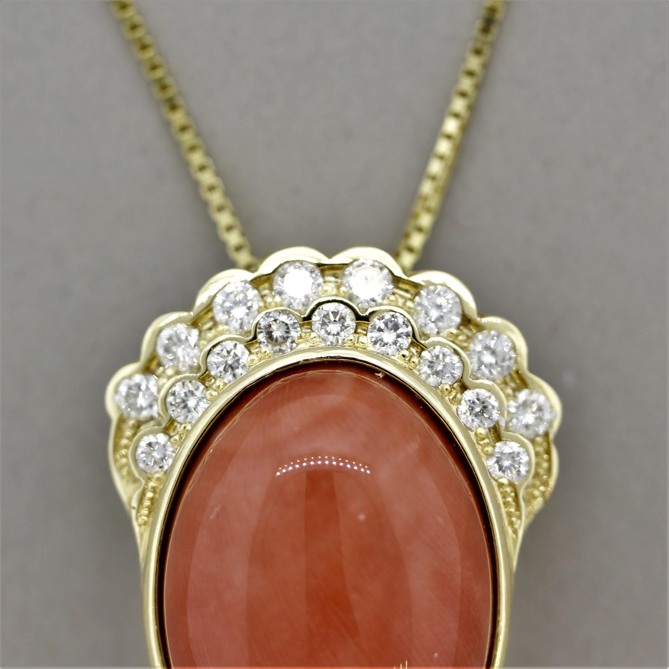 An impressive pendant featuring a large piece of natural coral weighing approximately 15 carats (21mm x 18mm). It has a bright orangy-pink color typical of fine coral from the Mediterranean Sea. It is accented by 1.60 carats of round brilliant-cut