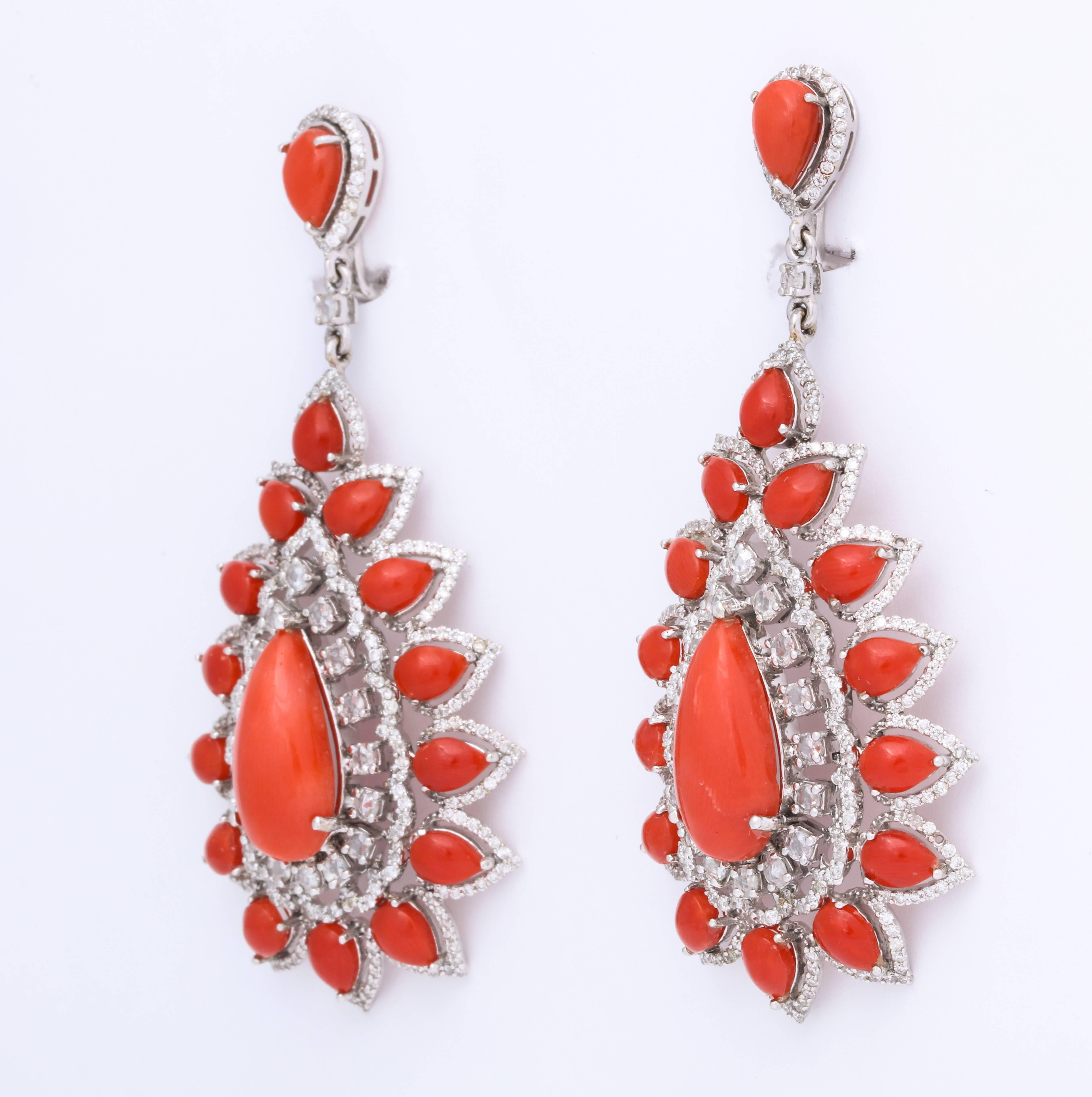18kt white gold, coral and diamond (4.49cts) earrings.  Perfectly matched, bright orange coral pear shape cabochons are each surrounded by diamonds.  The delicate setting makes these earrings appear to float just below the ear.