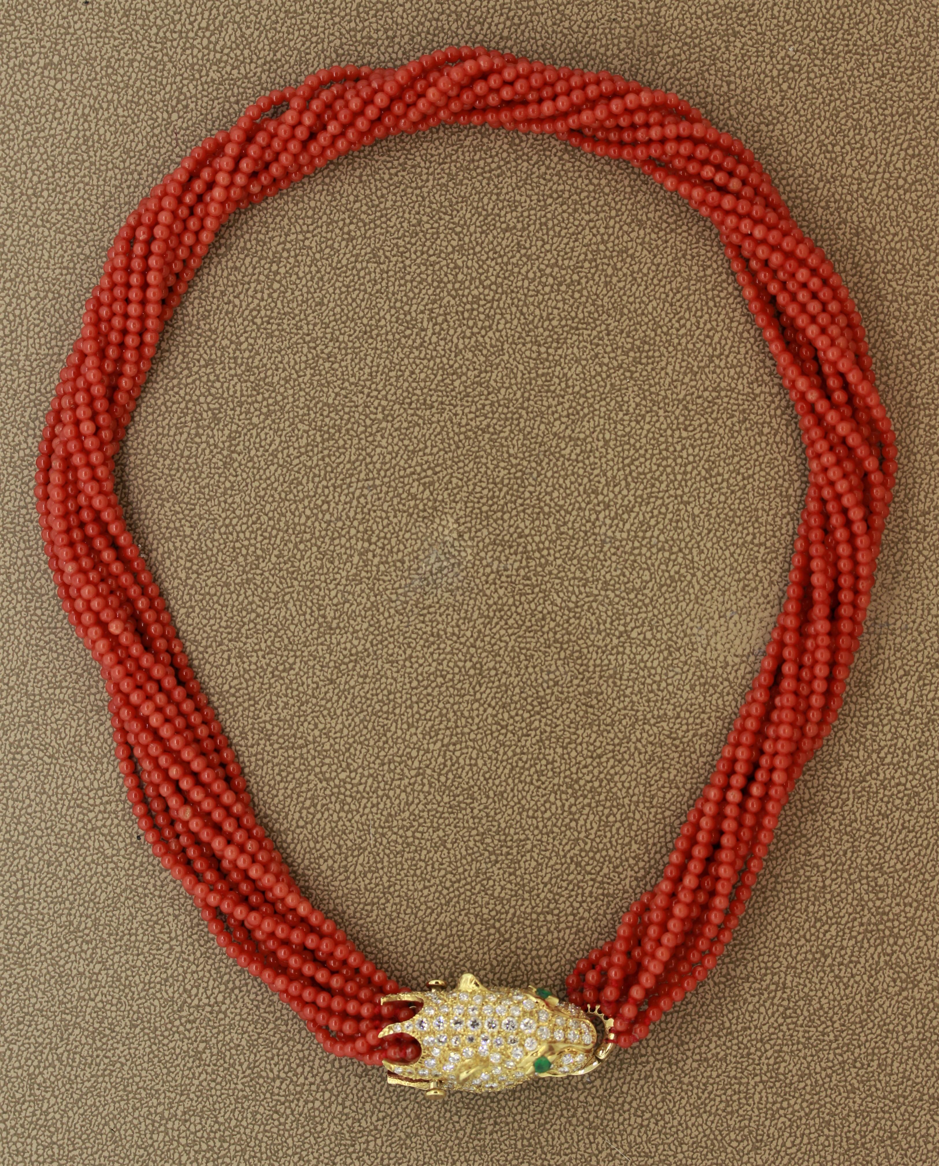 A fine quality necklace featuring 12 strands of natural coral from the Mediterranean Sea. The clasp is hand fabricated in 18k yellow gold as a panther and features approximately 4 carats of round brilliant cut diamonds and 2 vivid green emeralds as